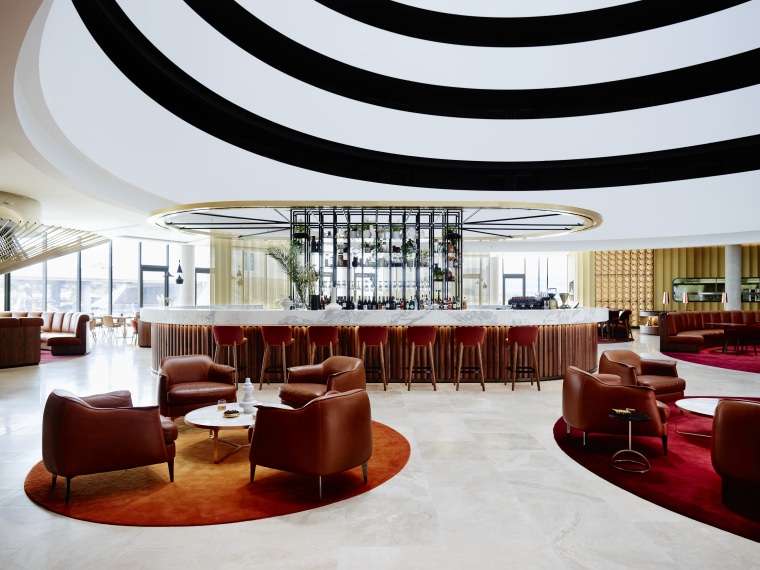 A curvaceous bar area provides the social focal ceiling, function hall, interior design, lobby, restaurant, table, white