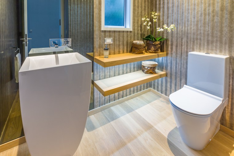 A wall-height smoked glass mirror behind the sculptural bathroom, floor, interior design, plumbing fixture, product design, room, toilet, toilet seat, gray