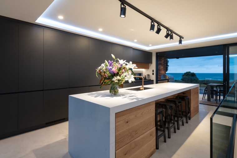 A white waterfall benchtop flowing over a wood-fronted architecture, countertop, interior design, kitchen, waterfall benchtop, timber, black cabinetry