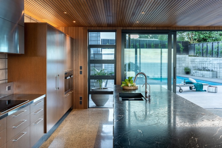 Open to the surrounding spaces, this kitchen is apartment, architecture, building, ceiling, countertop, daylighting, estate, floor, flooring, furniture, glass, hardwood, home, house, interior design, kitchen, property, real estate, residential area, room, window, wood