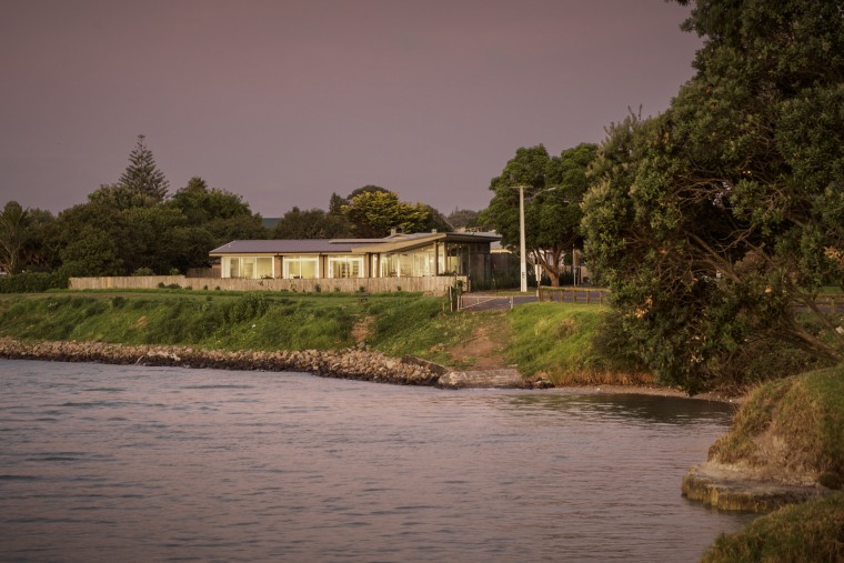 Following an "L" shape plan, the plan is bank, bayou, body of water, building, canal, channel, home, house, lake, landscape, natural landscape, reflection, river, rural area, sky, tree, water, water resources, watercourse, waterway, gray, brown