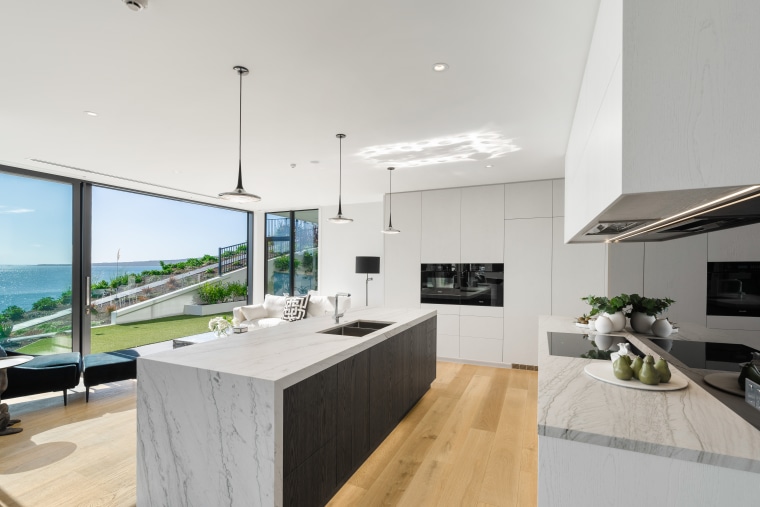 The fully integrated kitchen and scullery incorporate stunning apartment, architecture, building, ceiling, countertop, benshtop, stone top, integrated appliances, pendant lights, design, estate, floor, flooring, furniture, home, house, interior design, kitchen, living room, property, real estate, roof, room, table, wood flooring, gray
