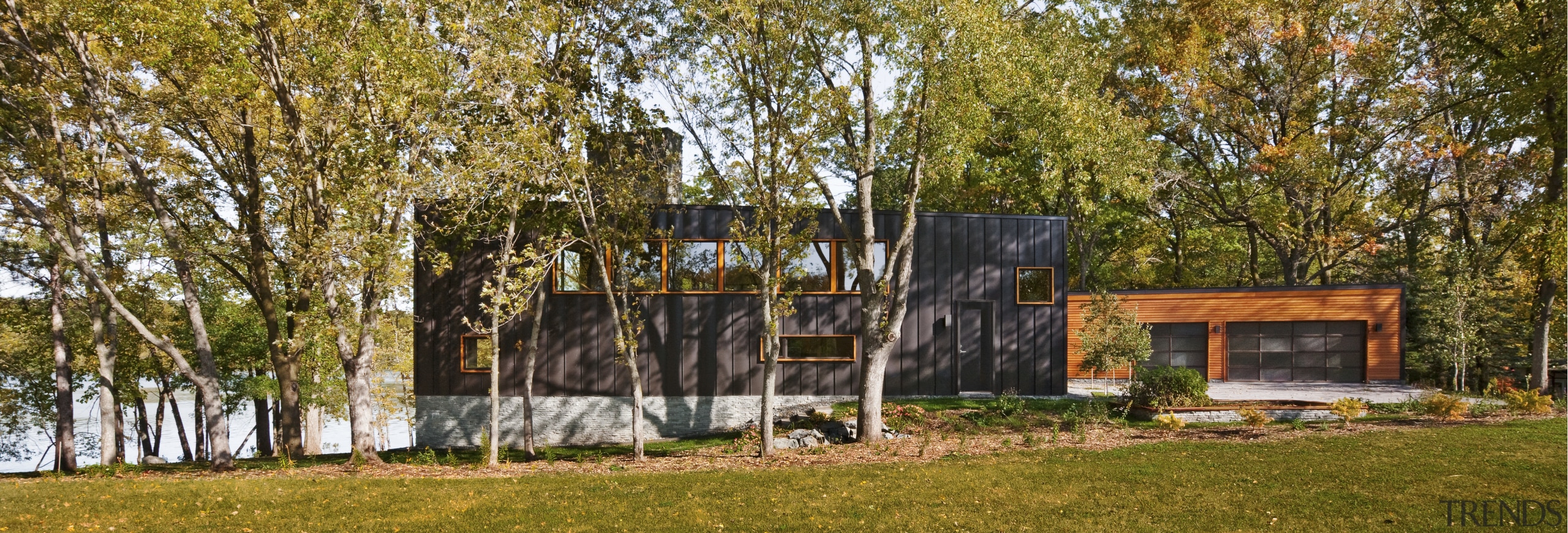 View of the exterior of the home featuring cottage, grass, home, house, landscape, property, real estate, shed, state park, tree, brown