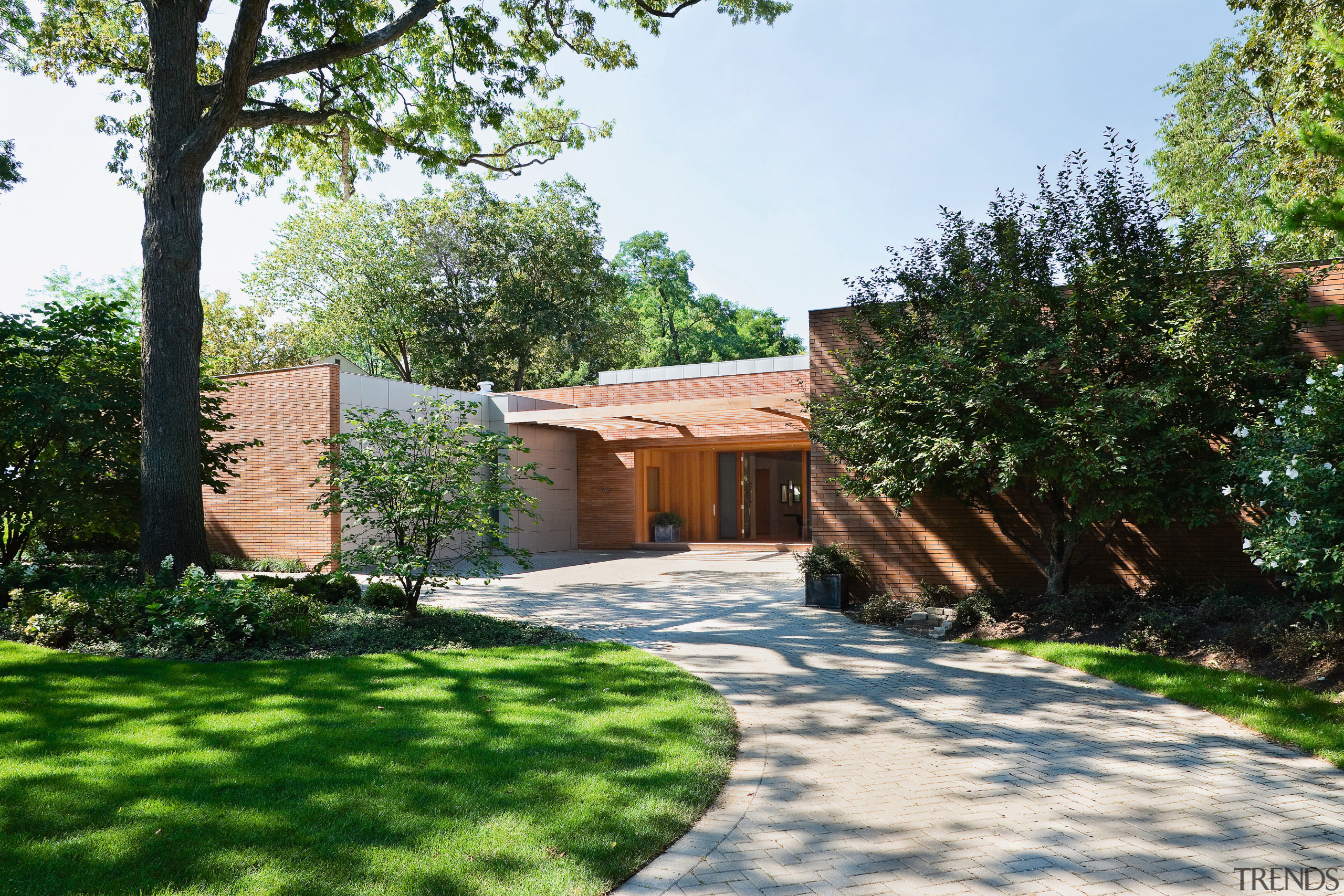 An exterior view of the entrance way to backyard, cottage, courtyard, estate, facade, garden, grass, home, house, landscape, landscaping, outdoor structure, property, real estate, residential area, tree, villa, walkway, yard, white, green