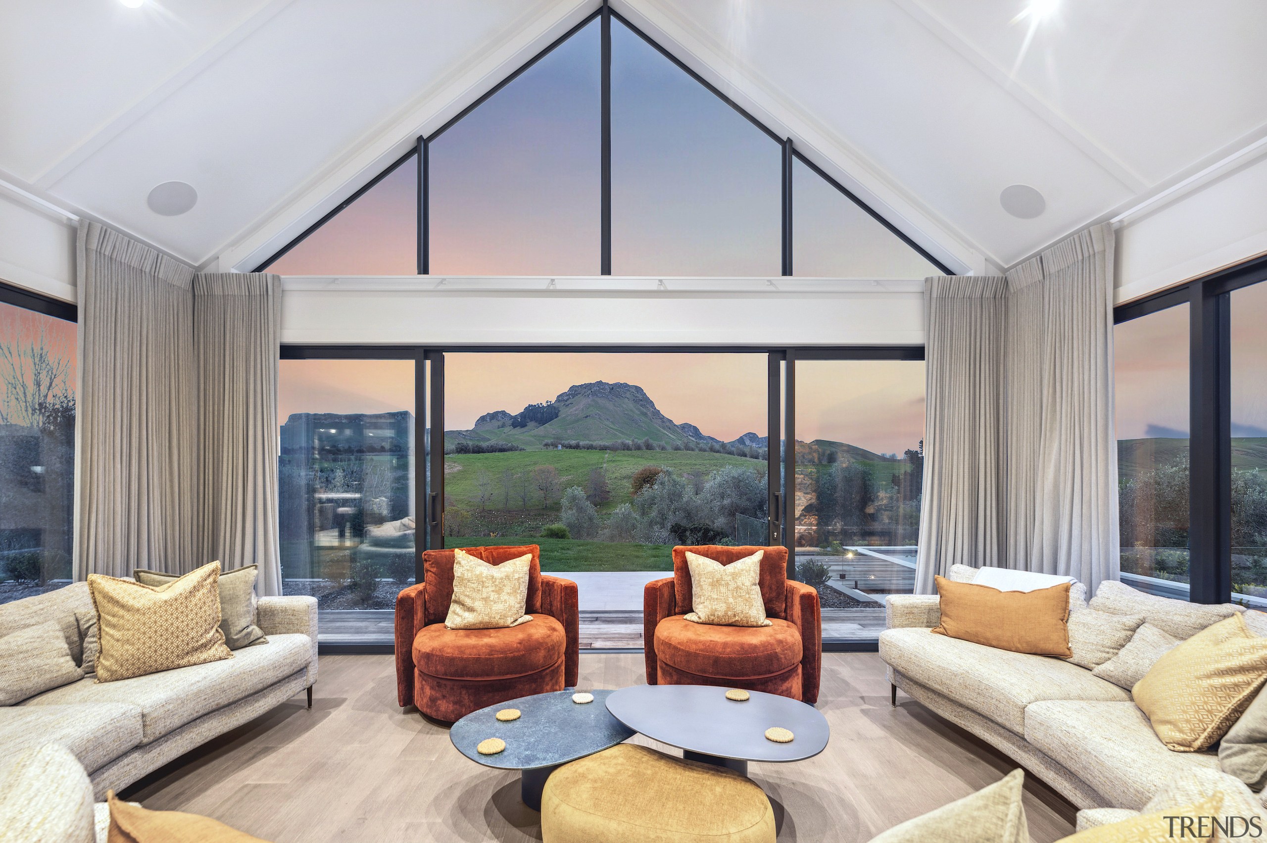 Living space with walls of glass capturing dusk 