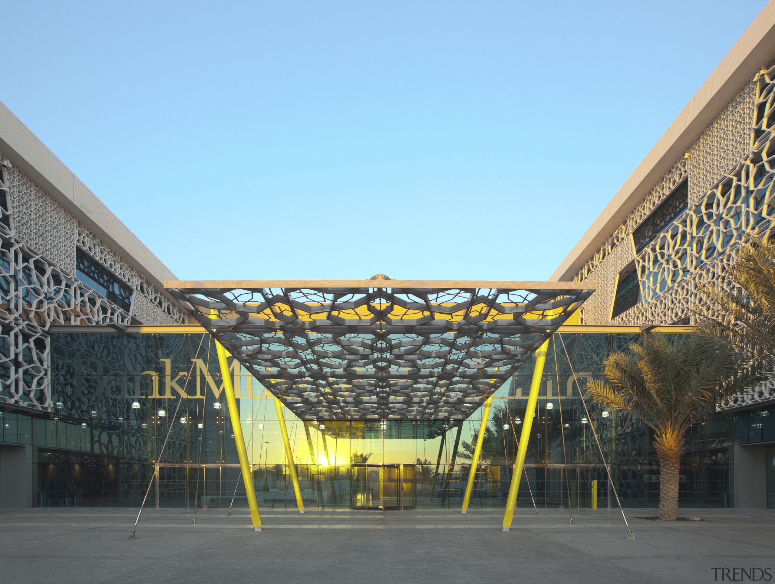 View of exterior with yellow beams at entrance. architecture, building, city, daytime, facade, landmark, metropolitan area, mixed use, roof, sky, structure, urban area, teal