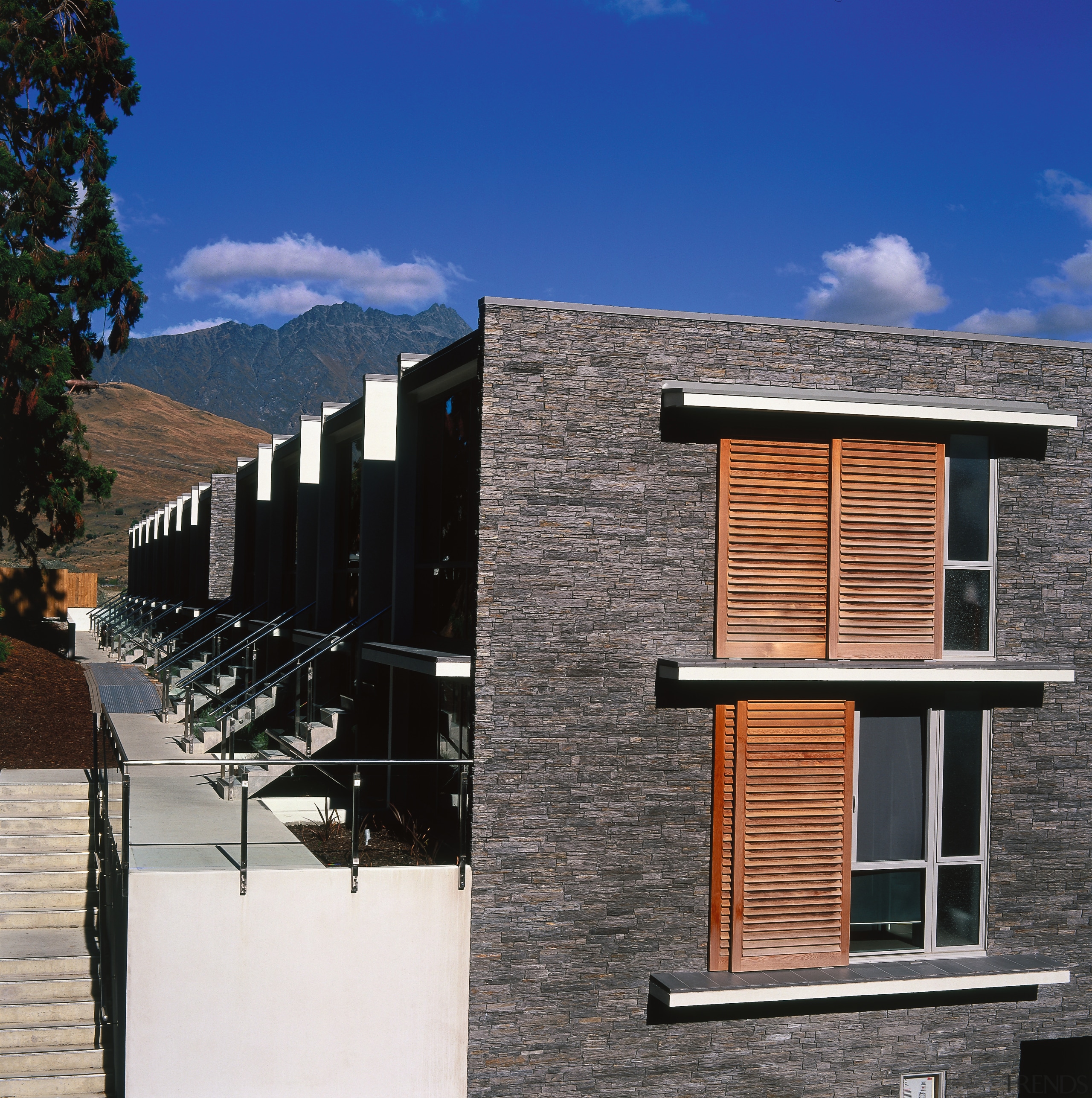 Exterior view of apartments showing stone cladding, timber architecture, building, elevation, facade, home, house, property, real estate, residential area, roof, siding, sky, window, black, blue