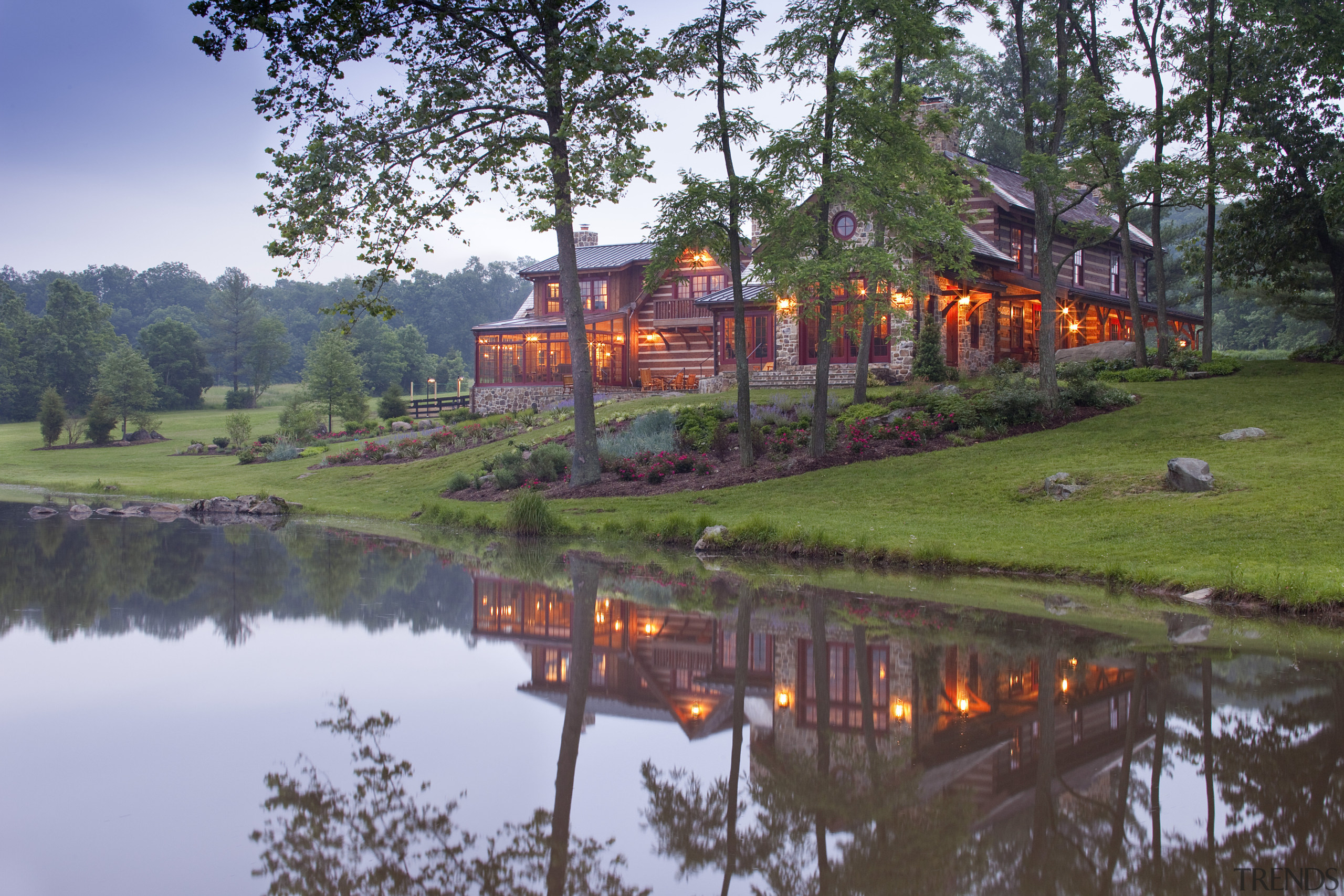 View of home with lake in foreground. - cottage, estate, evening, home, lake, landscape, nature, plant, pond, real estate, reflection, sky, tourist attraction, tree, water