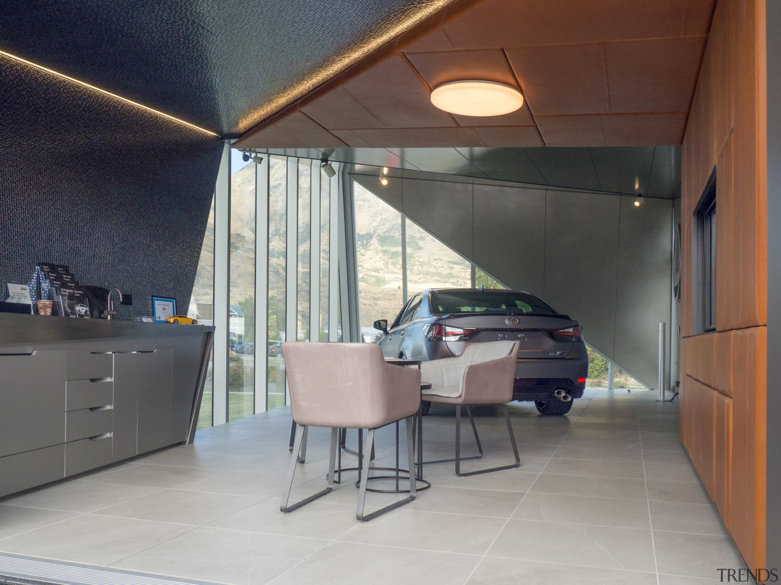 The one-car showroom space is equally sculptural on architecture, building, ceiling, daylighting, floor, furniture, house, interior design, property, roof, room, shade, wall, gray