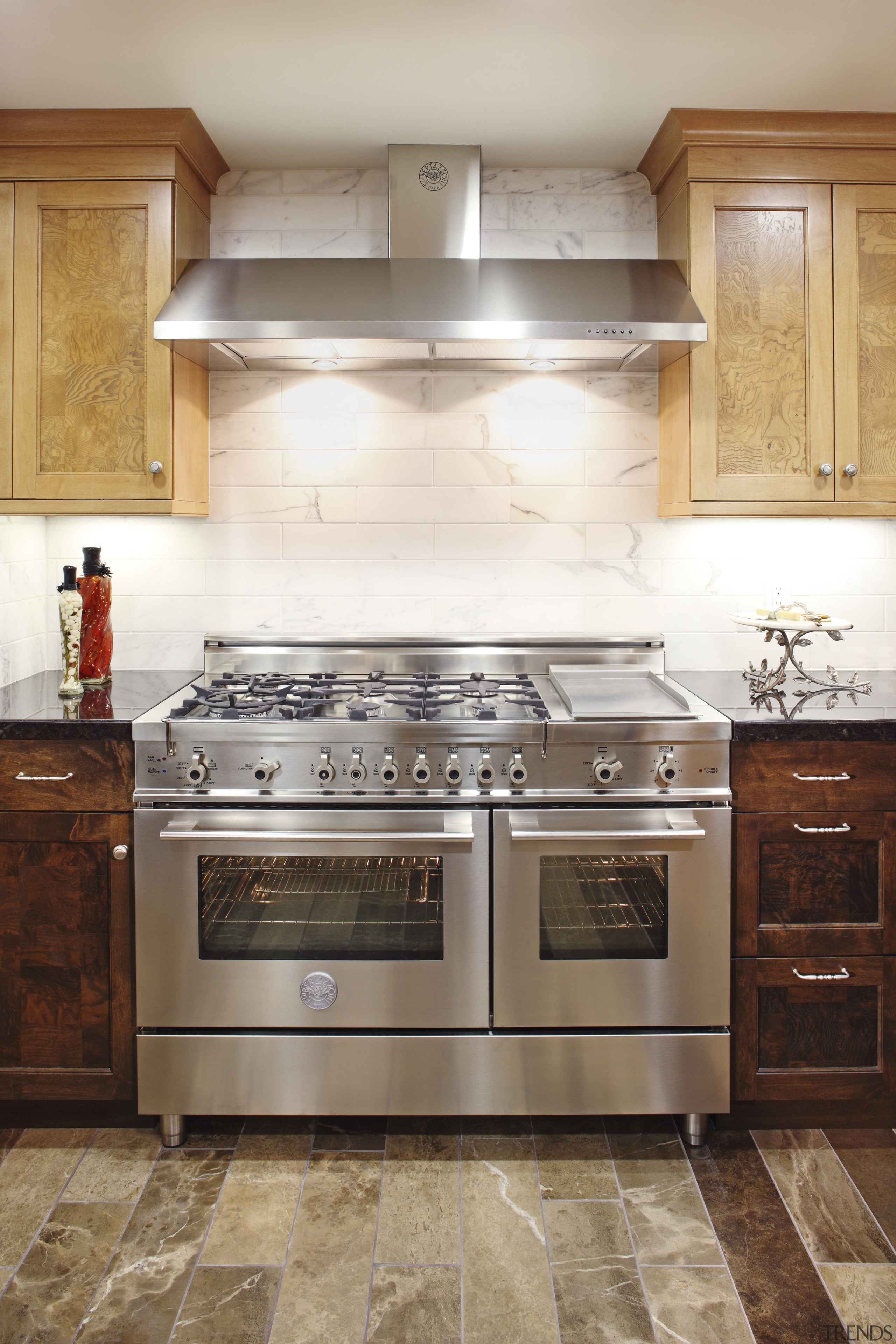 View of a contemporary kitchen which features a cabinetry, countertop, cuisine classique, floor, flooring, furniture, gas stove, hardwood, home appliance, interior design, kitchen, kitchen appliance, kitchen stove, major appliance, oven, room, tile, under cabinet lighting, wood flooring, white, brown