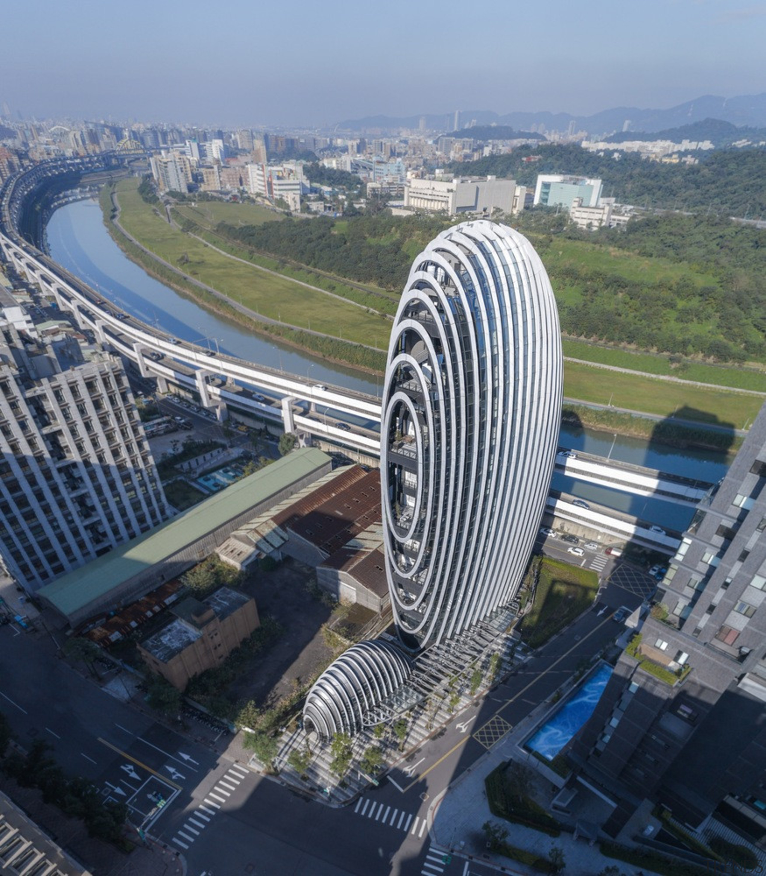 The building's design drew inspiration from pebbles along aerial photography, architecture, bird's-eye view, building, city, cityscape, commercial building, corporate headquarters, headquarters, landmark, landscape, metropolis, metropolitan area, mixed-use, sky, skyscraper, stadium, tower, tower block, urban area, urban design, gray, blue