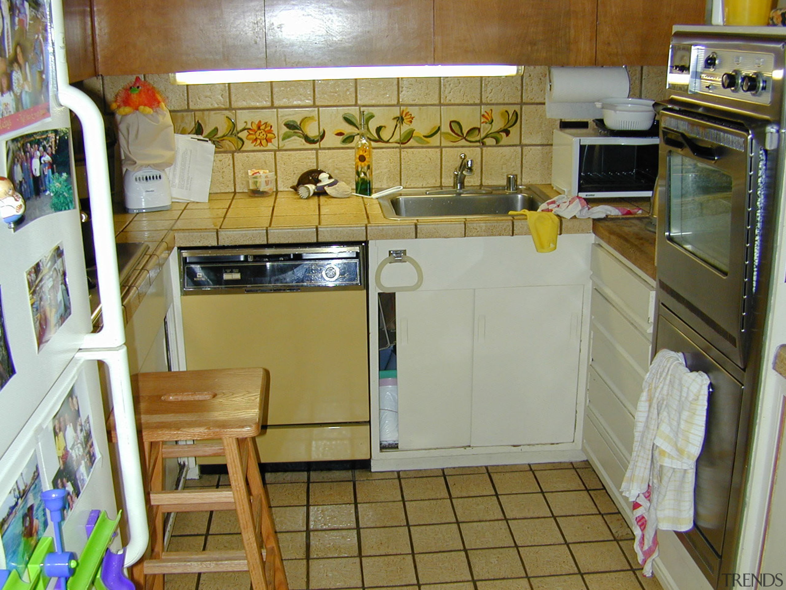 A view of the cramped and awkward original countertop, floor, flooring, kitchen, major appliance, property, room, brown, gray