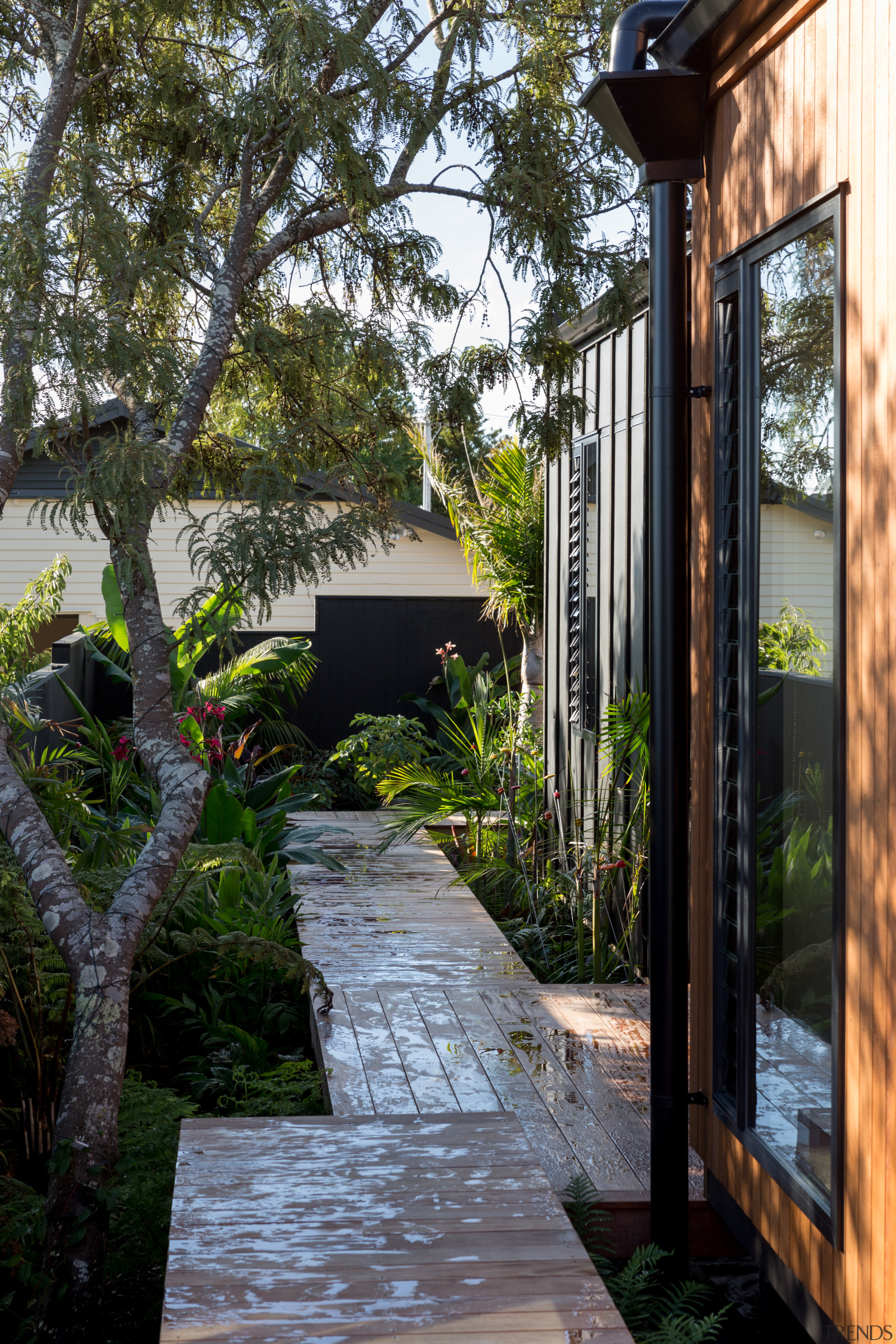 Raised boardwalks run around the side of this architecture, backyard, cottage, courtyard, garden, home, house, landscaping, outdoor structure, plant, real estate, tree, walkway, yard, black