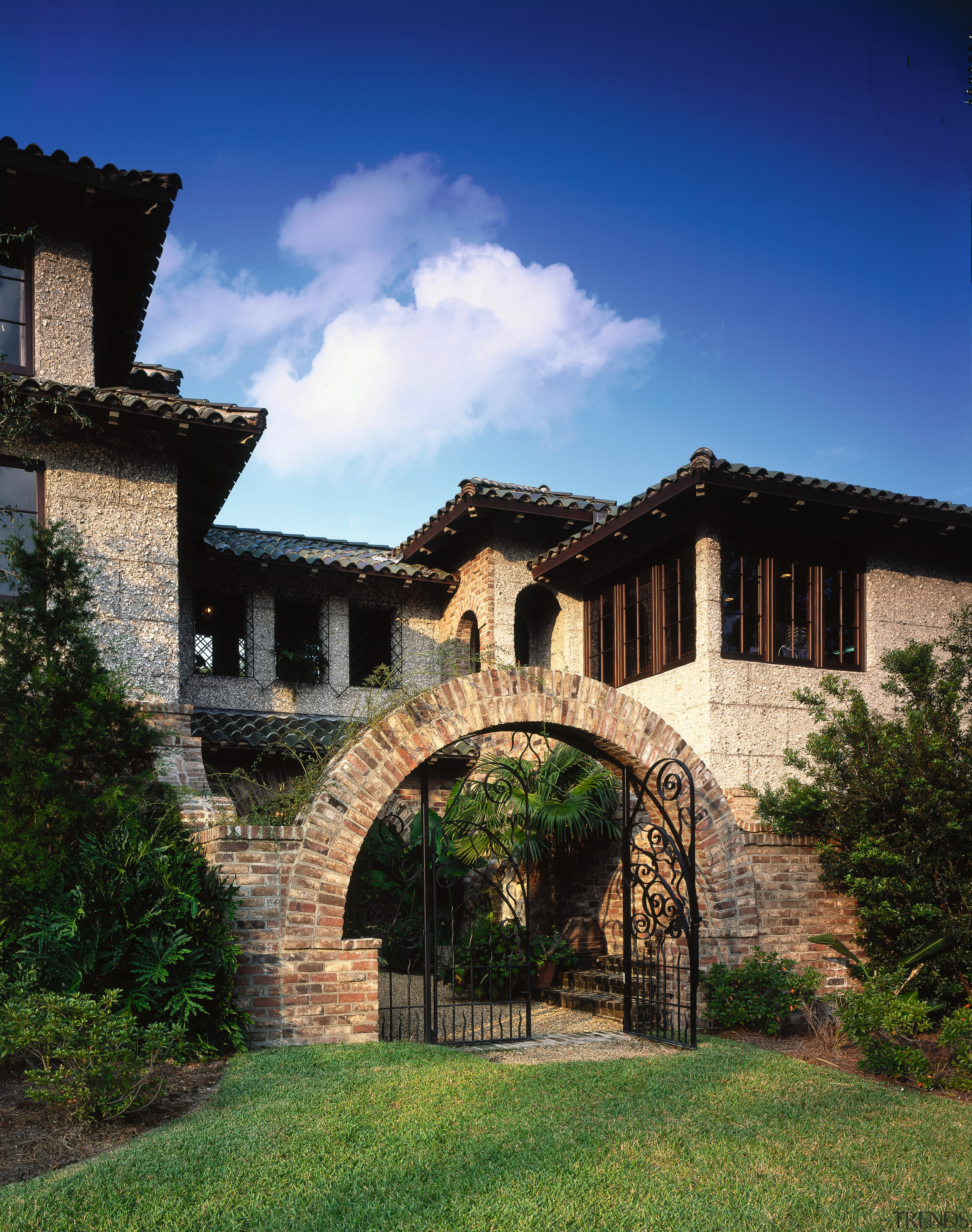 The archway is designed to look as if arch, building, cottage, estate, facade, hacienda, home, house, mansion, medieval architecture, property, real estate, sky, tree, villa, village, wall, blue