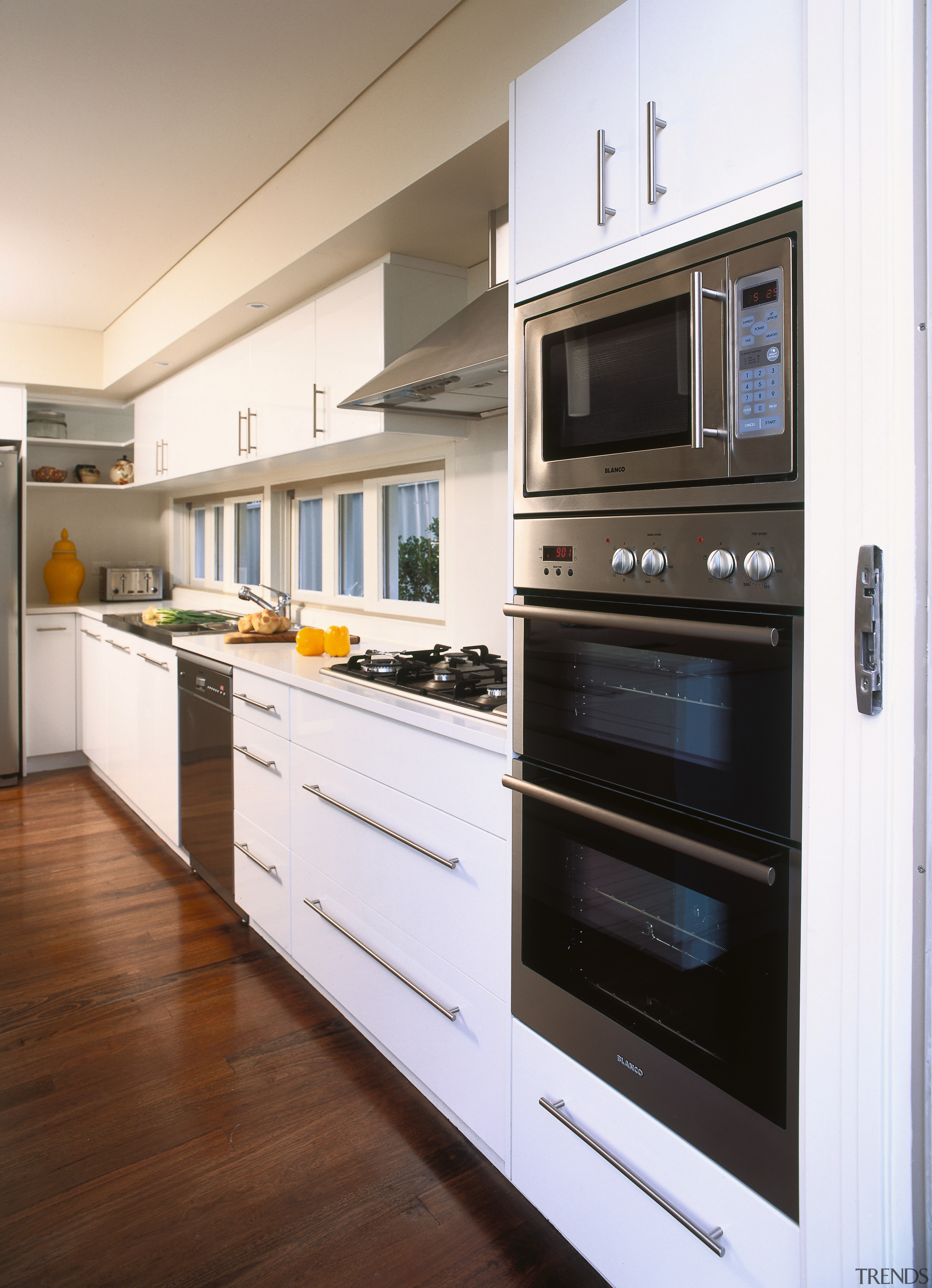 A view of a kitchen area, wooden flooring, cabinetry, countertop, home appliance, kitchen, kitchen appliance, kitchen stove, major appliance, microwave oven, oven, white, brown