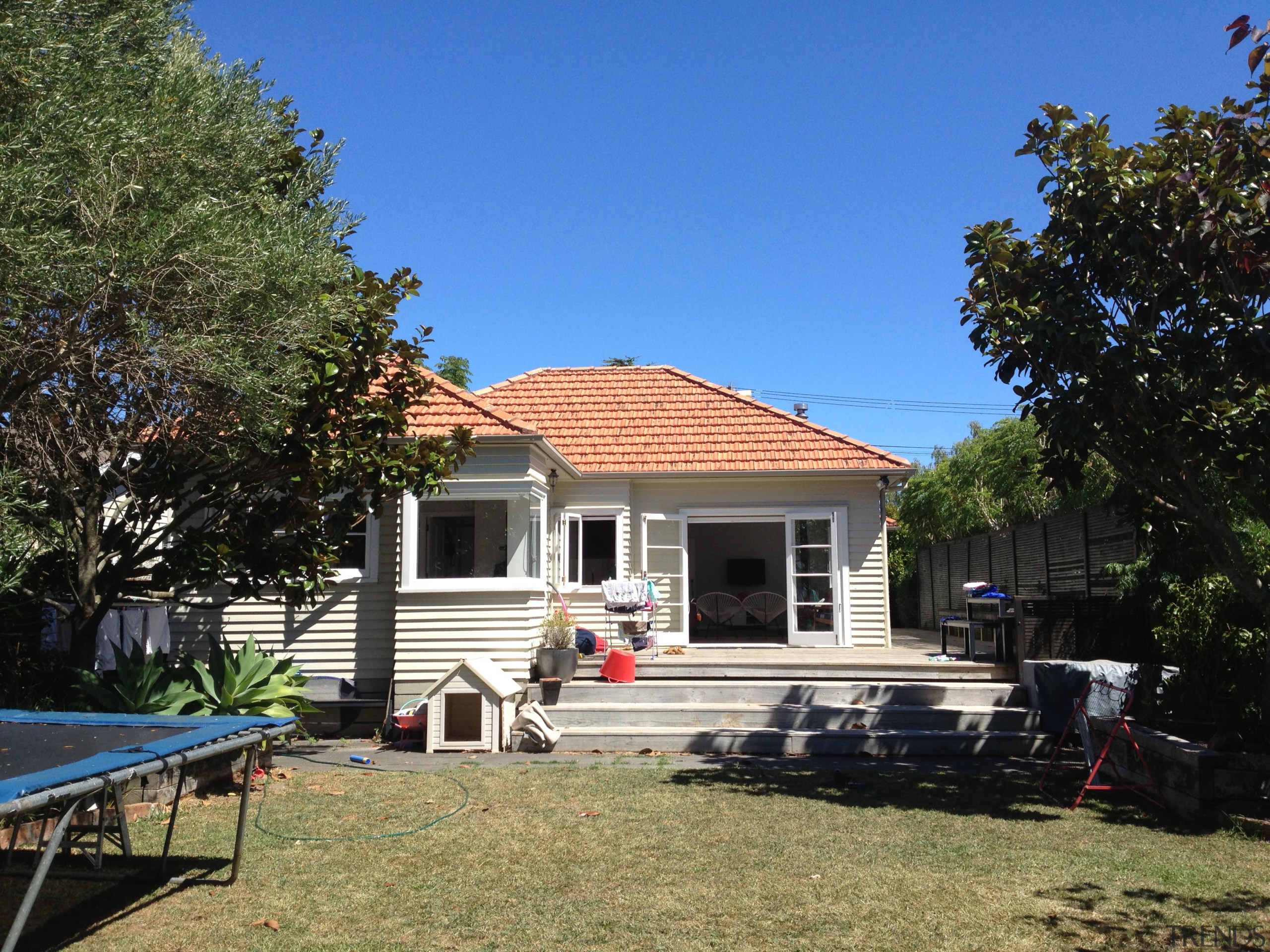 Before a major renovation took place, a small backyard, cottage, estate, facade, farmhouse, home, house, landscape, outdoor structure, property, real estate, residential area, roof, siding, sky, tree, villa, yard, black