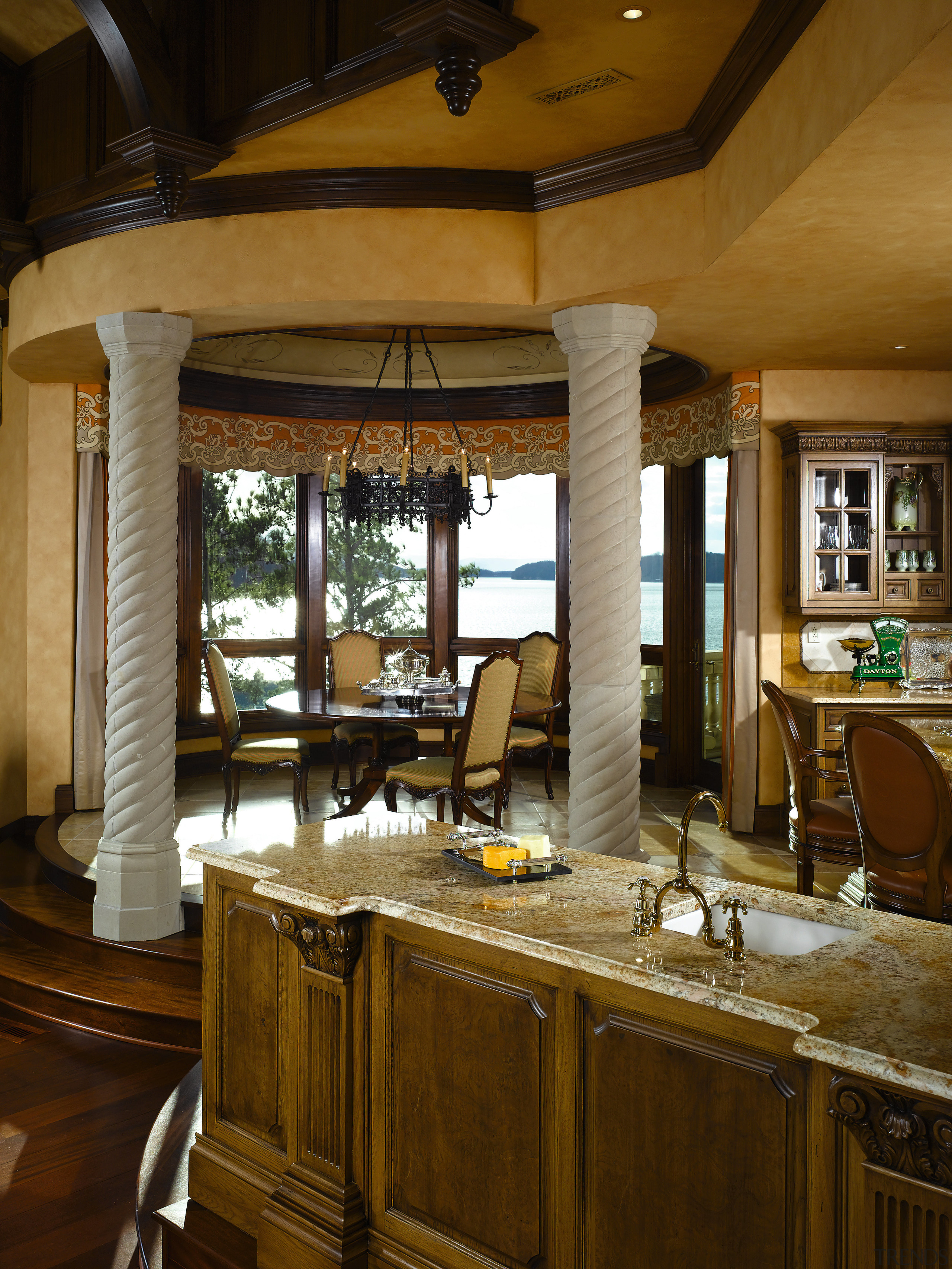 A view of this elegant kitchen featuring gold cabinetry, countertop, furniture, interior design, kitchen, room, window, brown