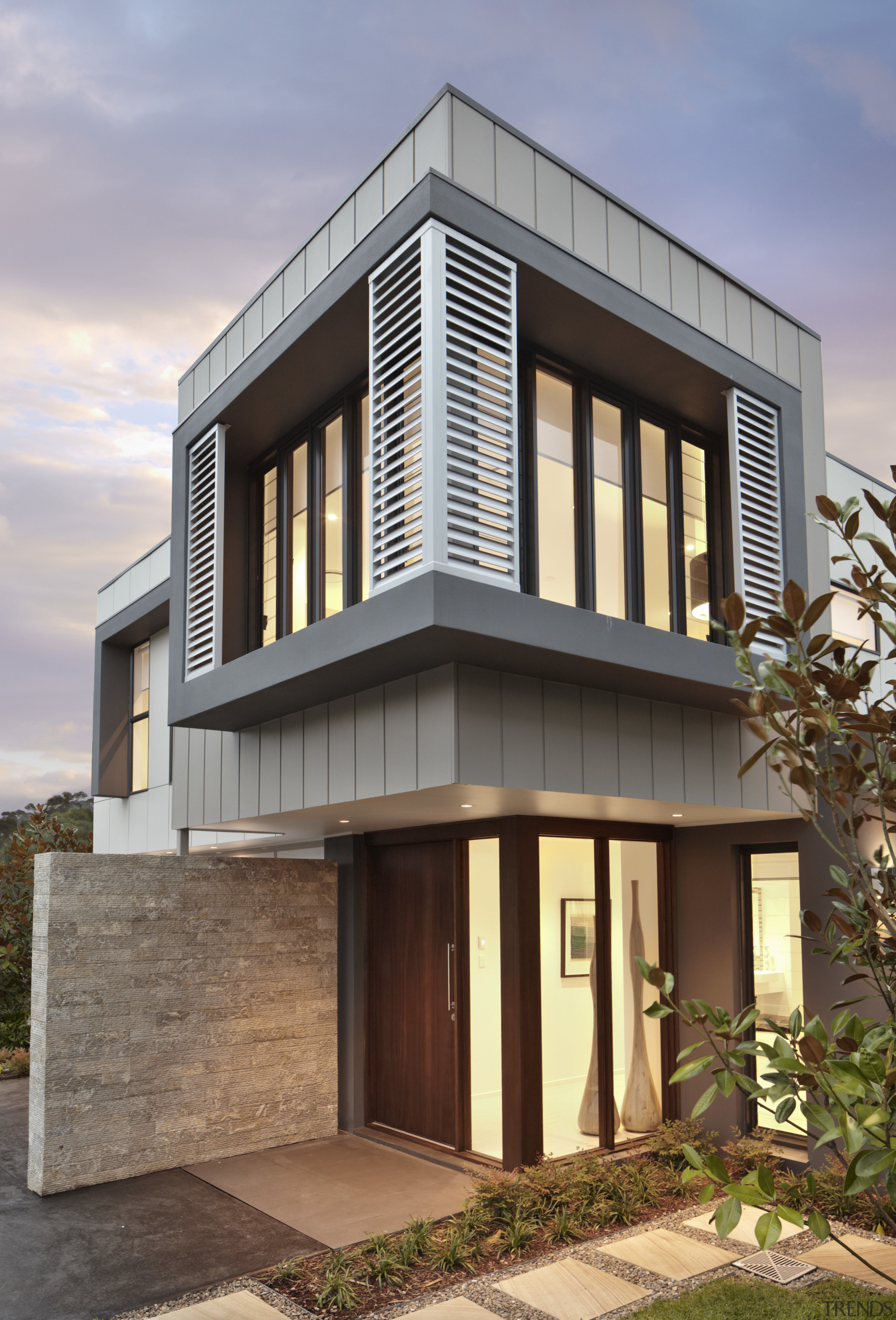 Exterior with stone wall at dusk. - Exterior architecture, building, commercial building, elevation, facade, home, house, property, real estate, residential area, siding, window