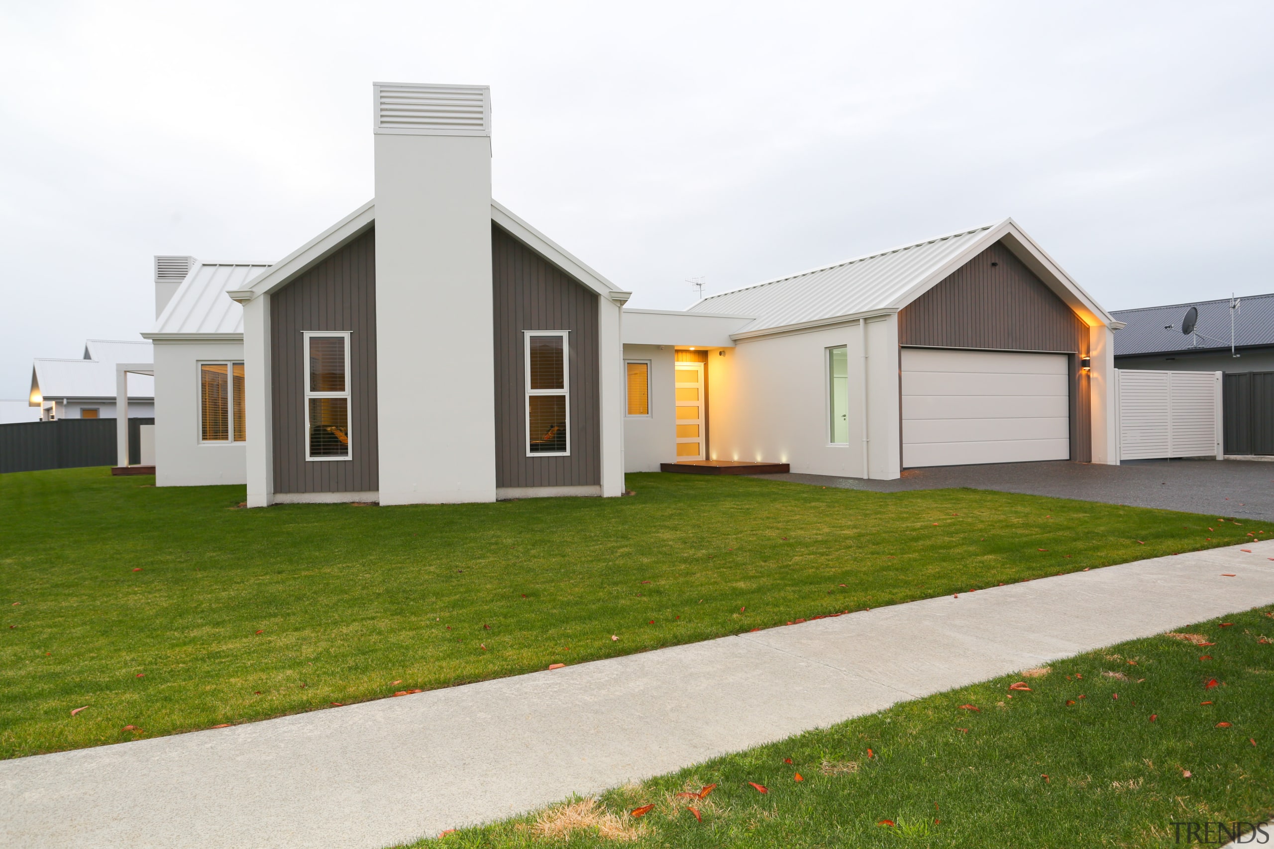 Contemporary pavilion-style home with gabled roofline and white-on-white architecture, cottage, elevation, estate, facade, farmhouse, grass, home, house, property, real estate, residential area, siding, white, brown