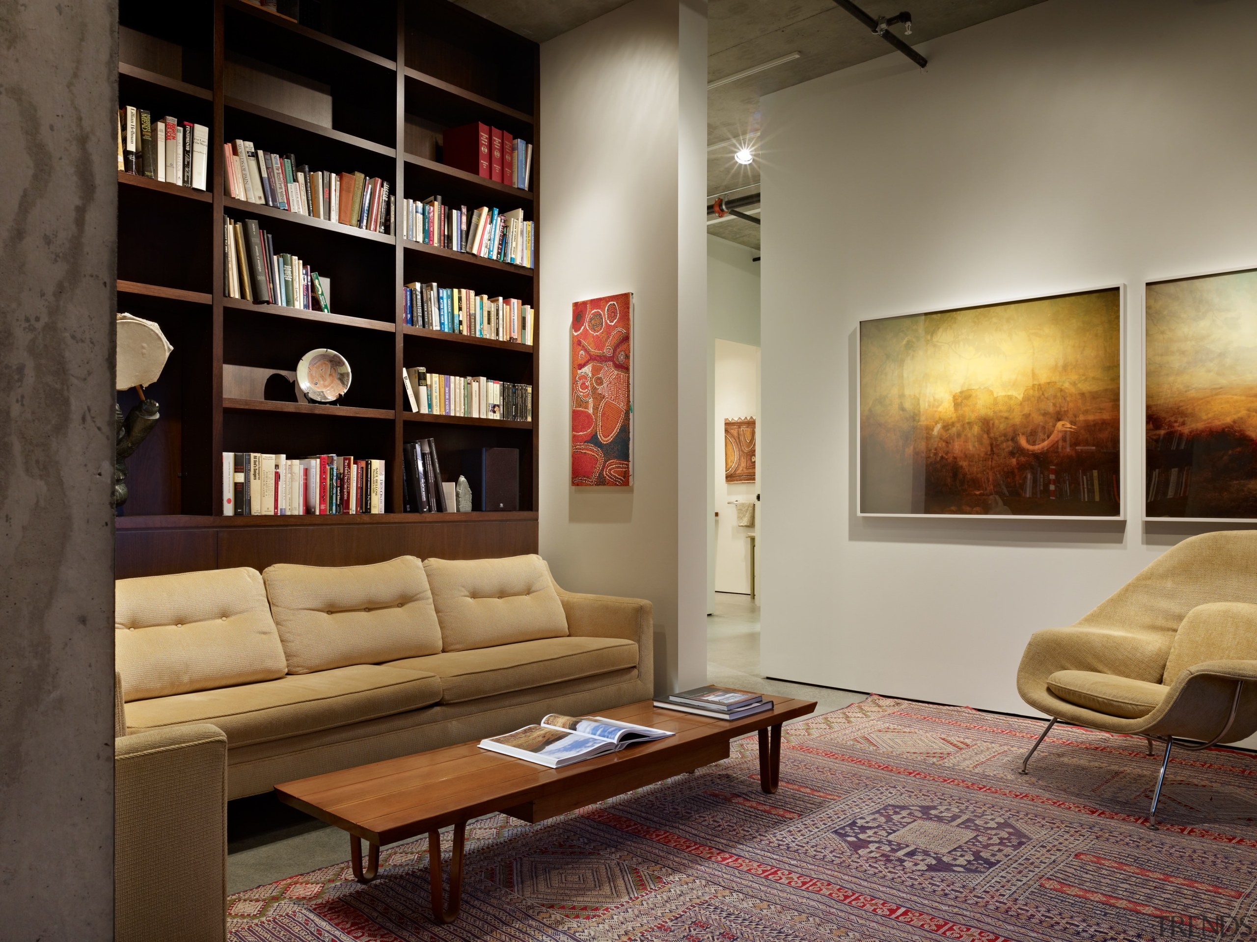 Lounge with floor rug, books on shelves and couch, floor, flooring, furniture, interior design, living room, room, shelving, table, wall, brown, black, gray