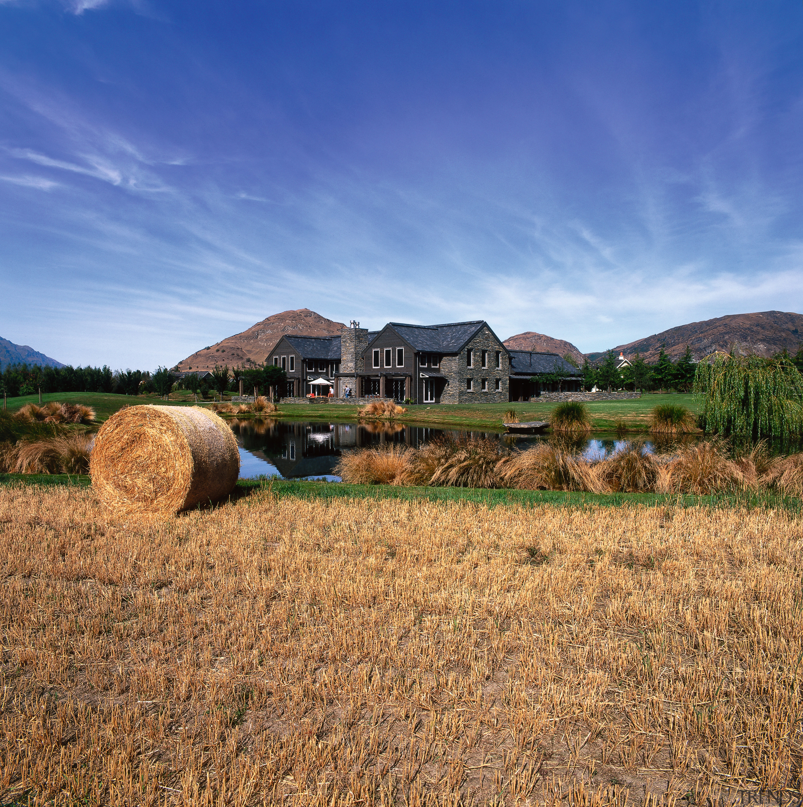 An exterior view of house with schist and agriculture, cloud, farm, field, grass, grass family, grassland, hay, highland, hill, home, house, landscape, mountain, plain, prairie, rural area, sky, straw, blue