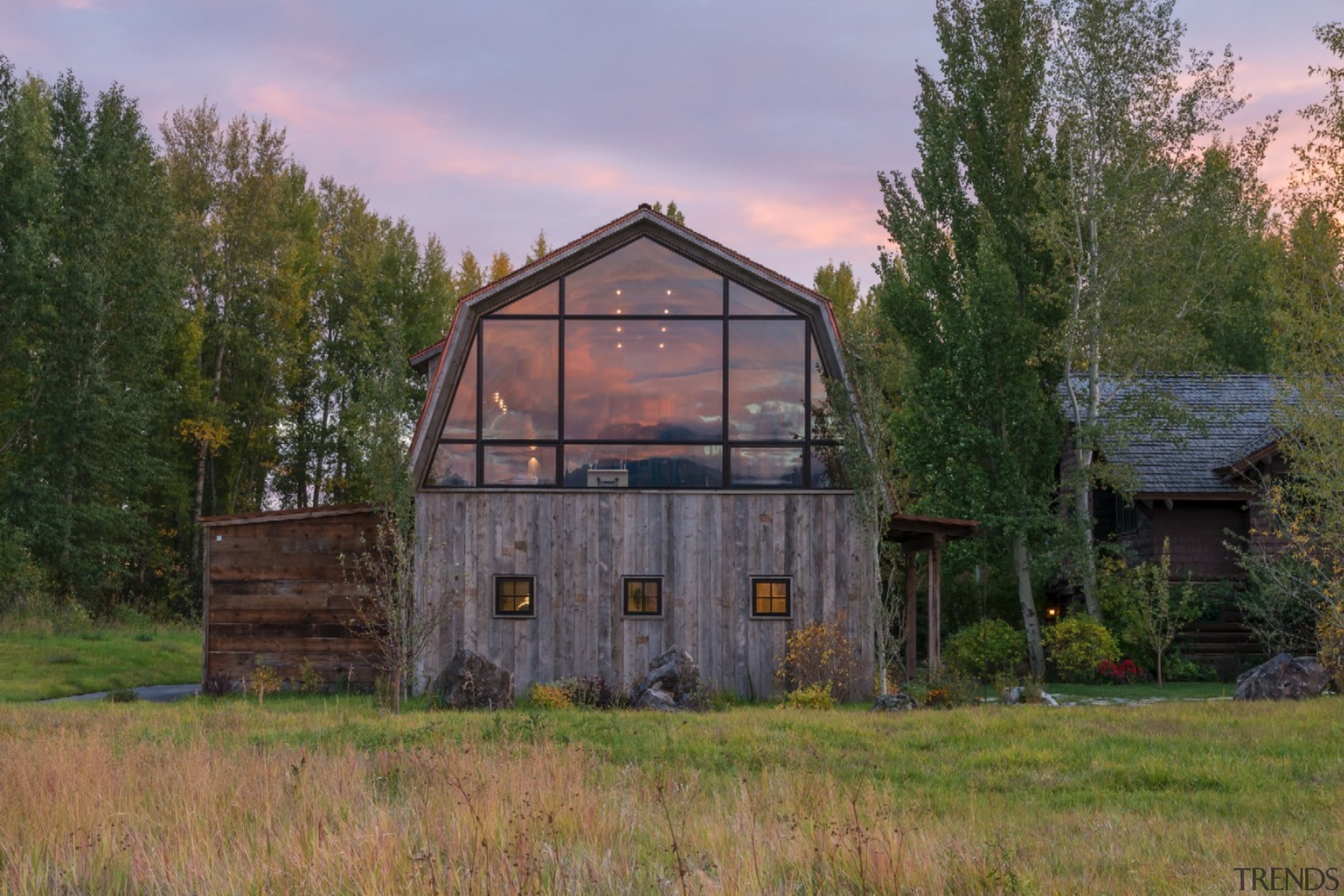 This large window looks out to the distant barn, cottage, farm, farmhouse, grass, home, house, hut, land lot, landscape, property, real estate, rural area, shack, shed, tree, brown