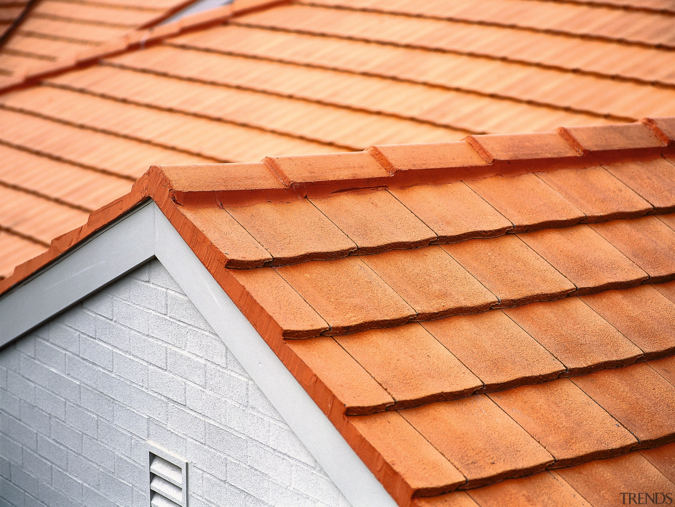 Closeup of terracotta coloured concrete roof tiles on brickwork, daylighting, line, lumber, material, outdoor structure, roof, siding, wood, wood stain, orange