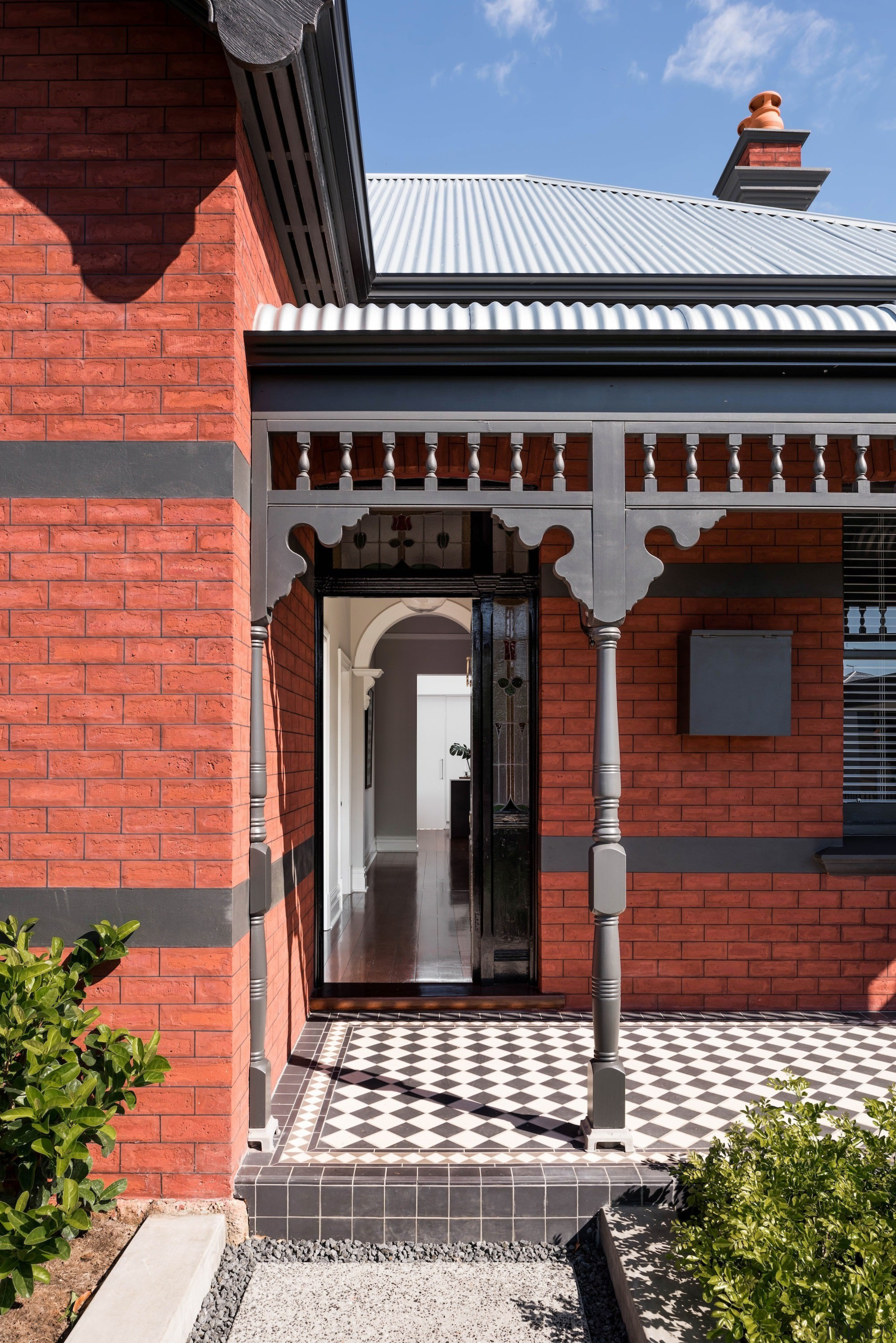 The front entrance retains many elements of the architecture, brick, building, facade, home, house, outdoor structure, porch, real estate, roof, window, red