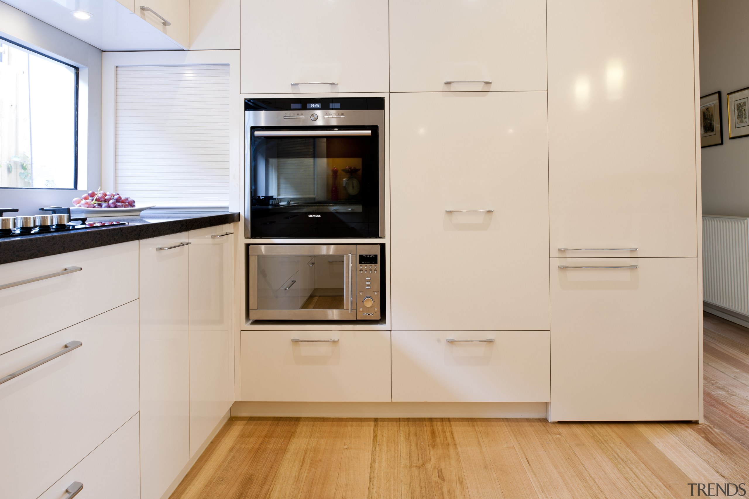 View of contemporary kitchen with white cabinetry and cabinetry, countertop, cuisine classique, floor, flooring, hardwood, home appliance, kitchen, kitchen appliance, major appliance, property, room, white