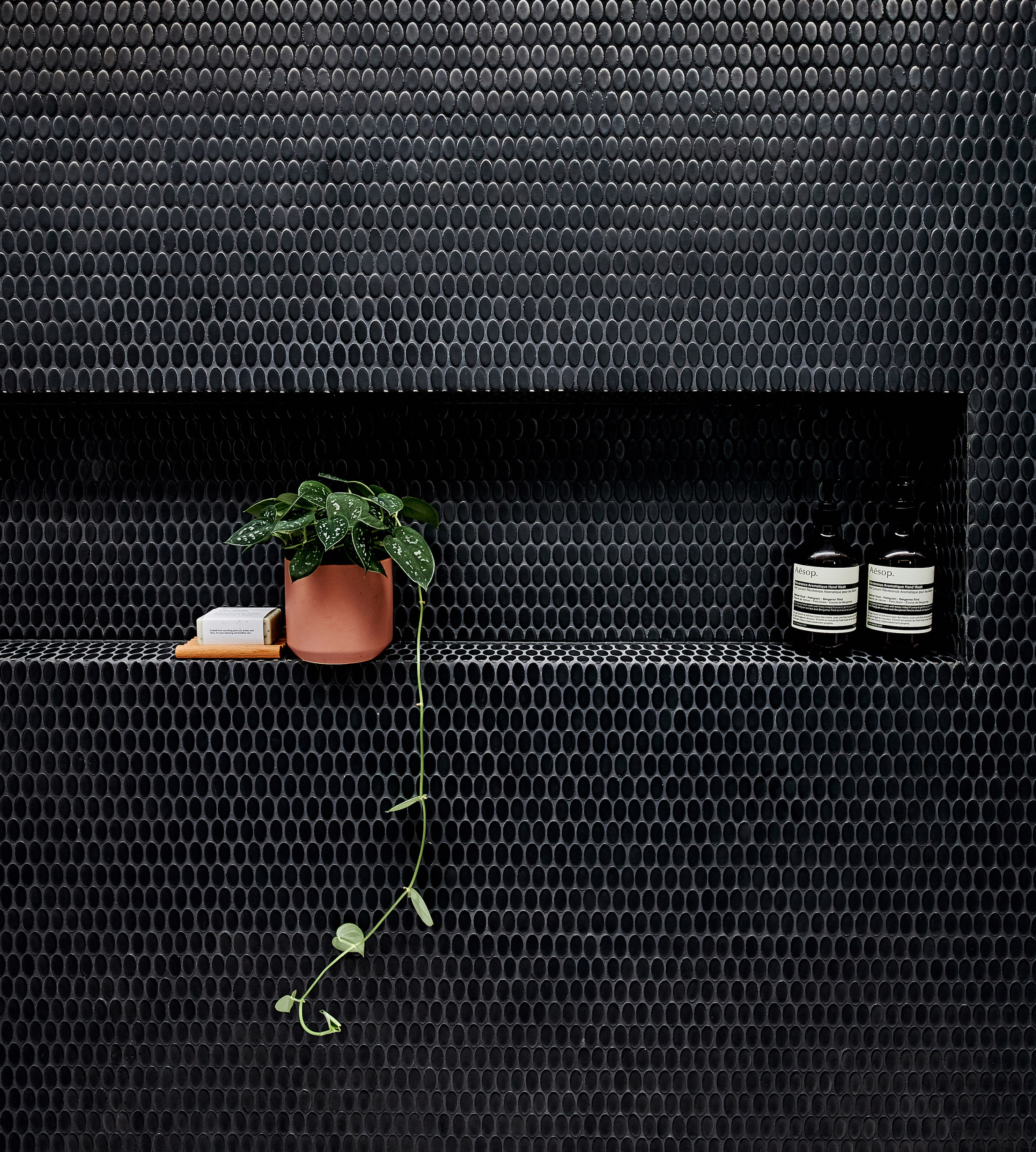 Matt black oval mosaic tiles feature in the 
