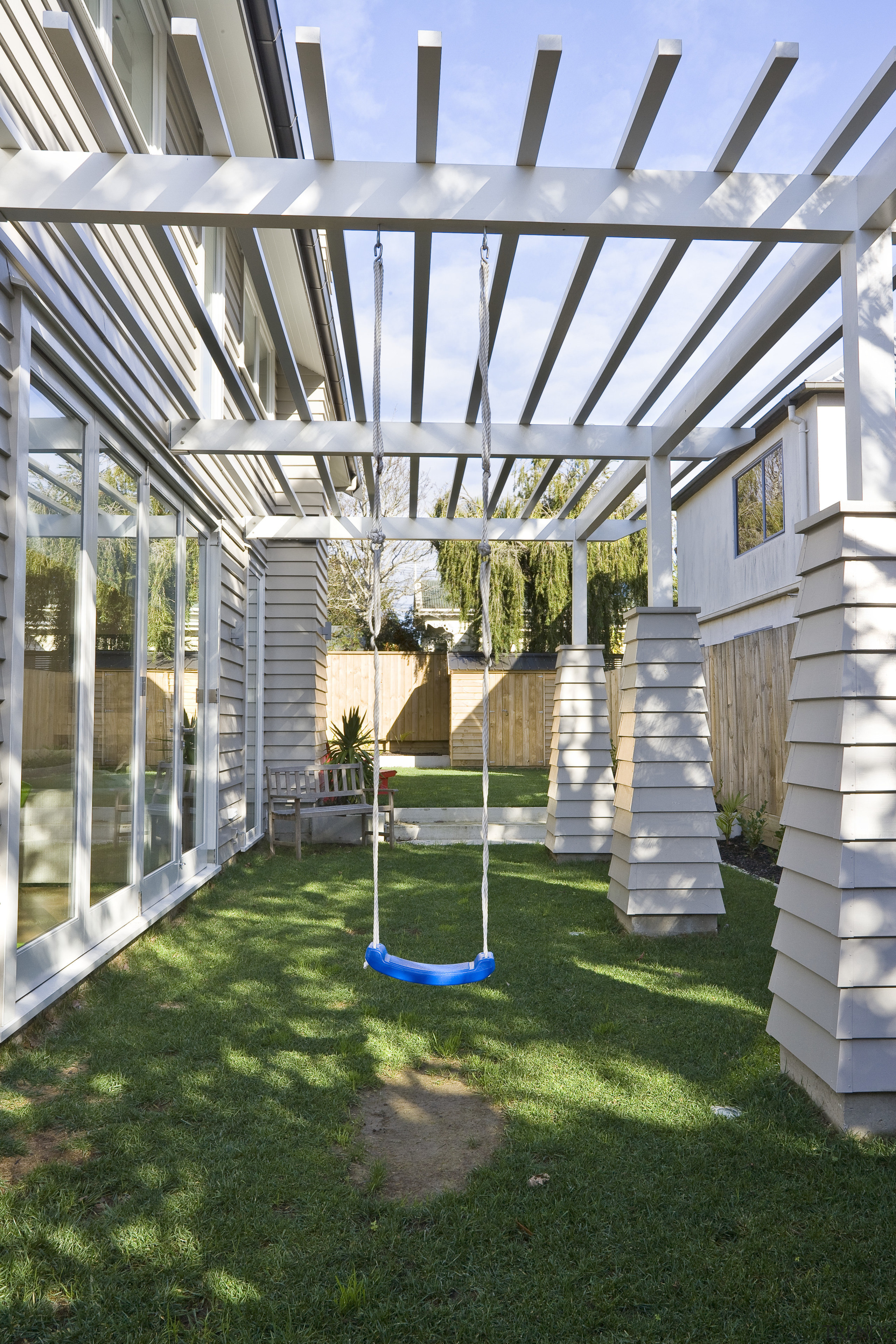 Exterior view of a new home designed by backyard, canopy, daylighting, grass, outdoor structure, pergola, structure, white