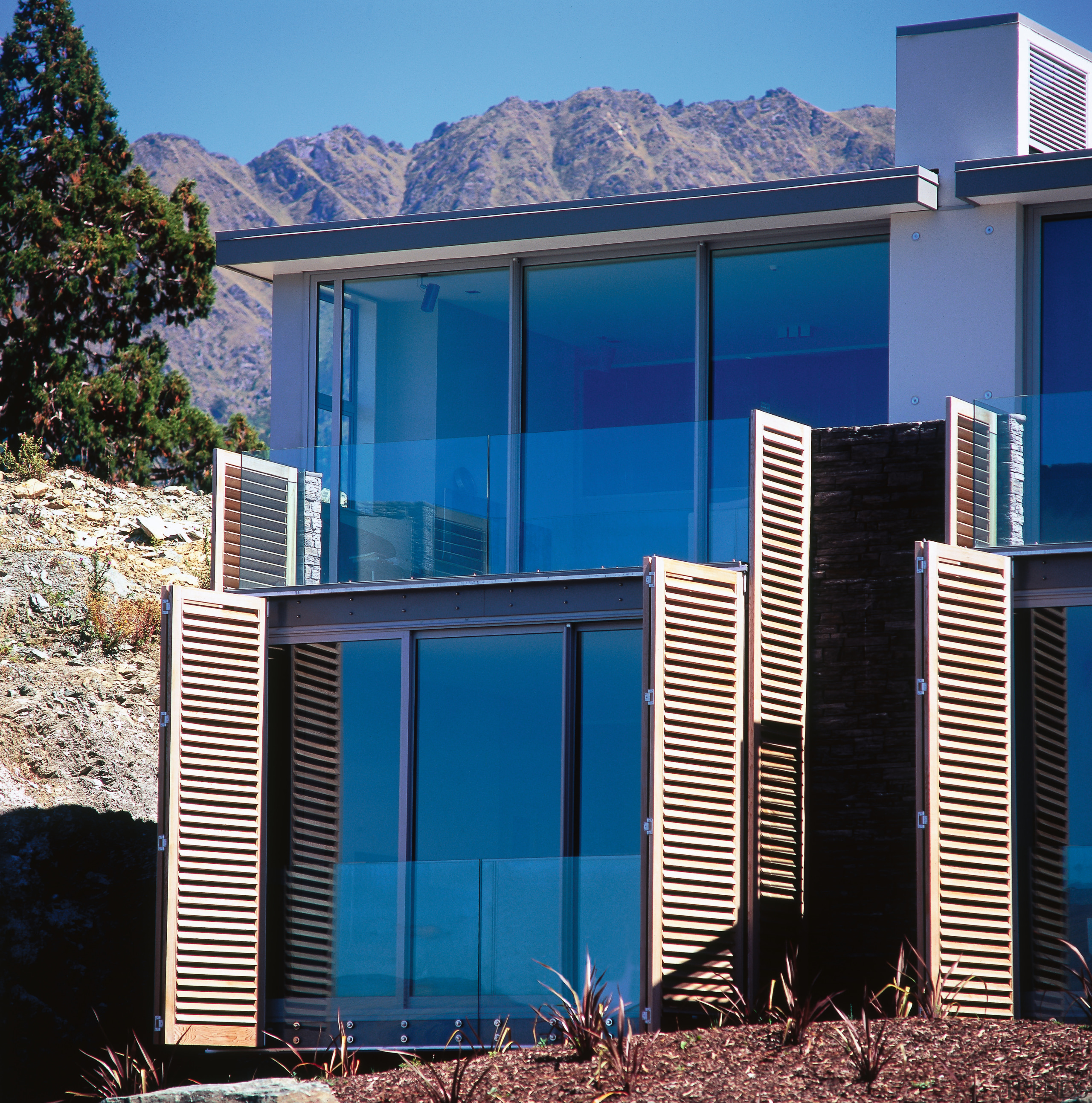 Two level apartment building overlooking mountains, with extensive architecture, building, elevation, facade, home, house, property, real estate, residential area, siding, window, blue