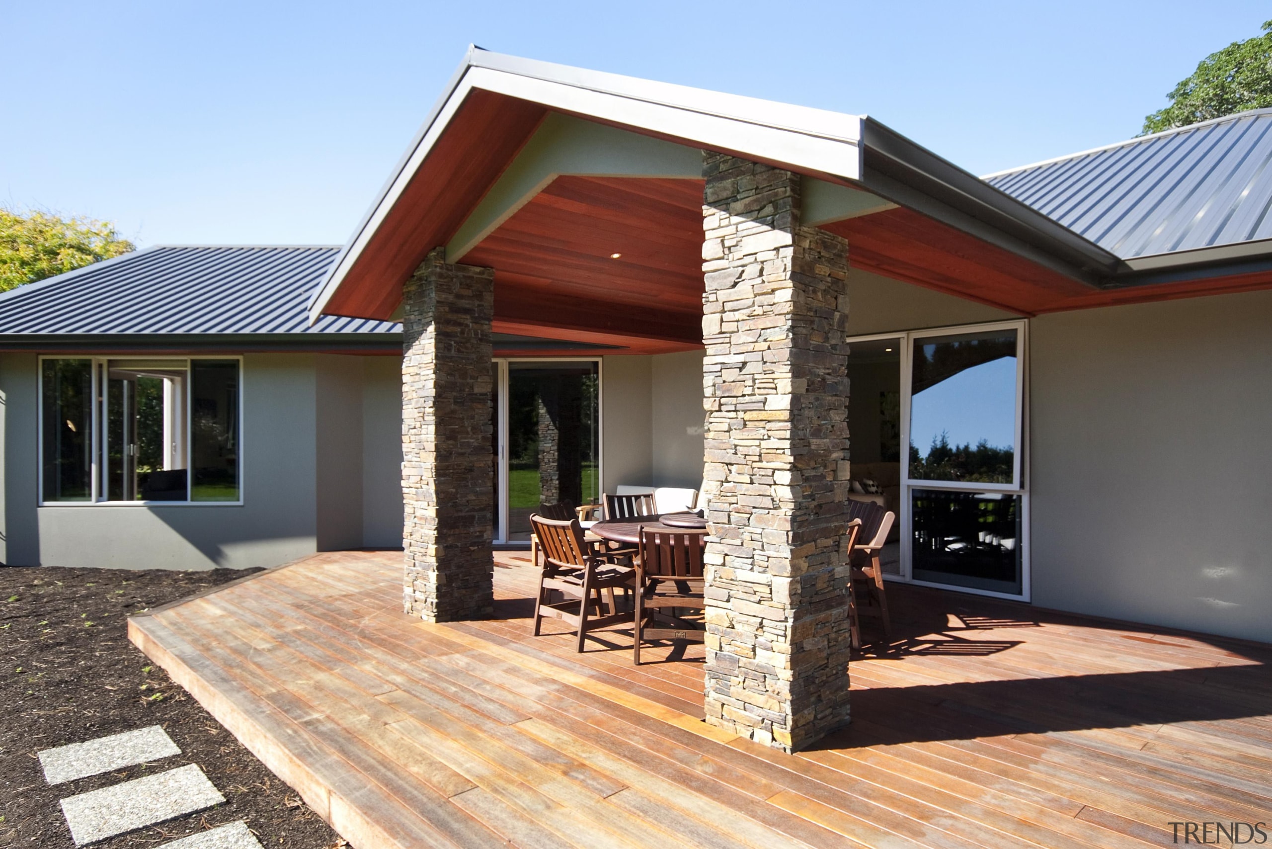 Covered outdoor living area with schist pillarsBuilt by facade, home, house, outdoor structure, property, real estate, siding