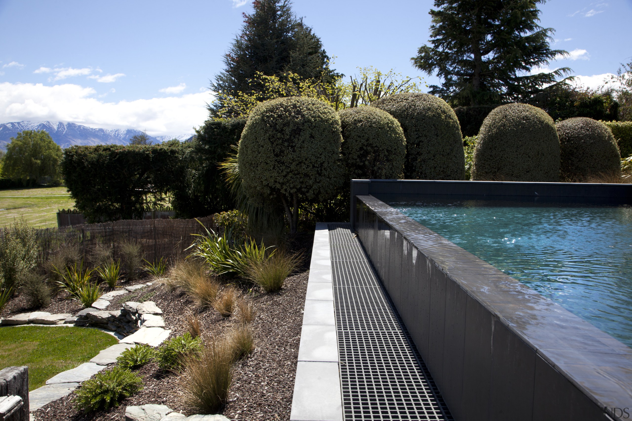 View of pool and landscaping. - View of estate, garden, grass, landscape, landscaping, lawn, outdoor structure, plant, real estate, reflection, swimming pool, tree, water, black