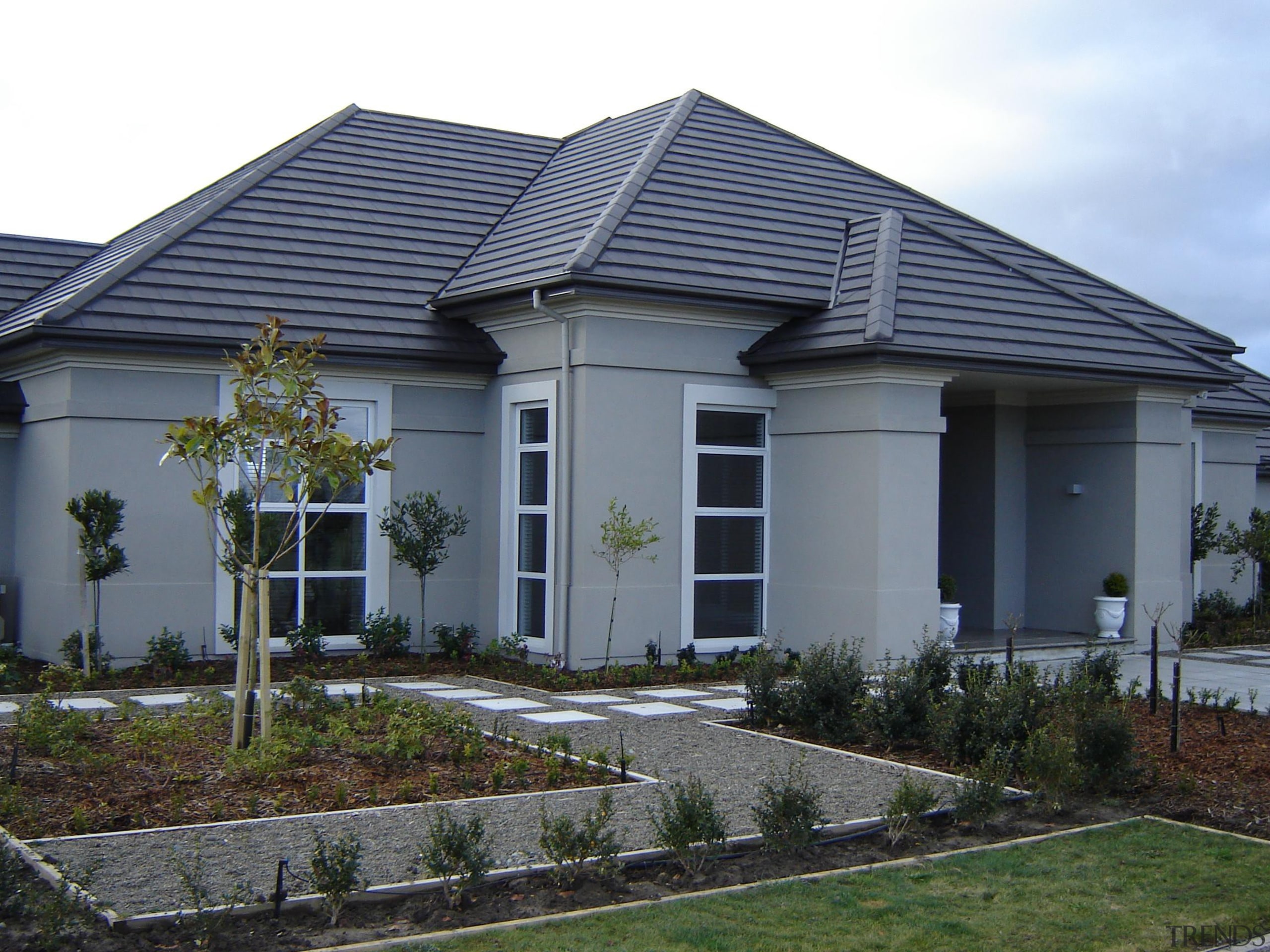 Feature entranceway of a generously proportioned plaster home cottage, elevation, estate, facade, home, house, landscaping, property, real estate, residential area, roof, siding, window, yard, gray