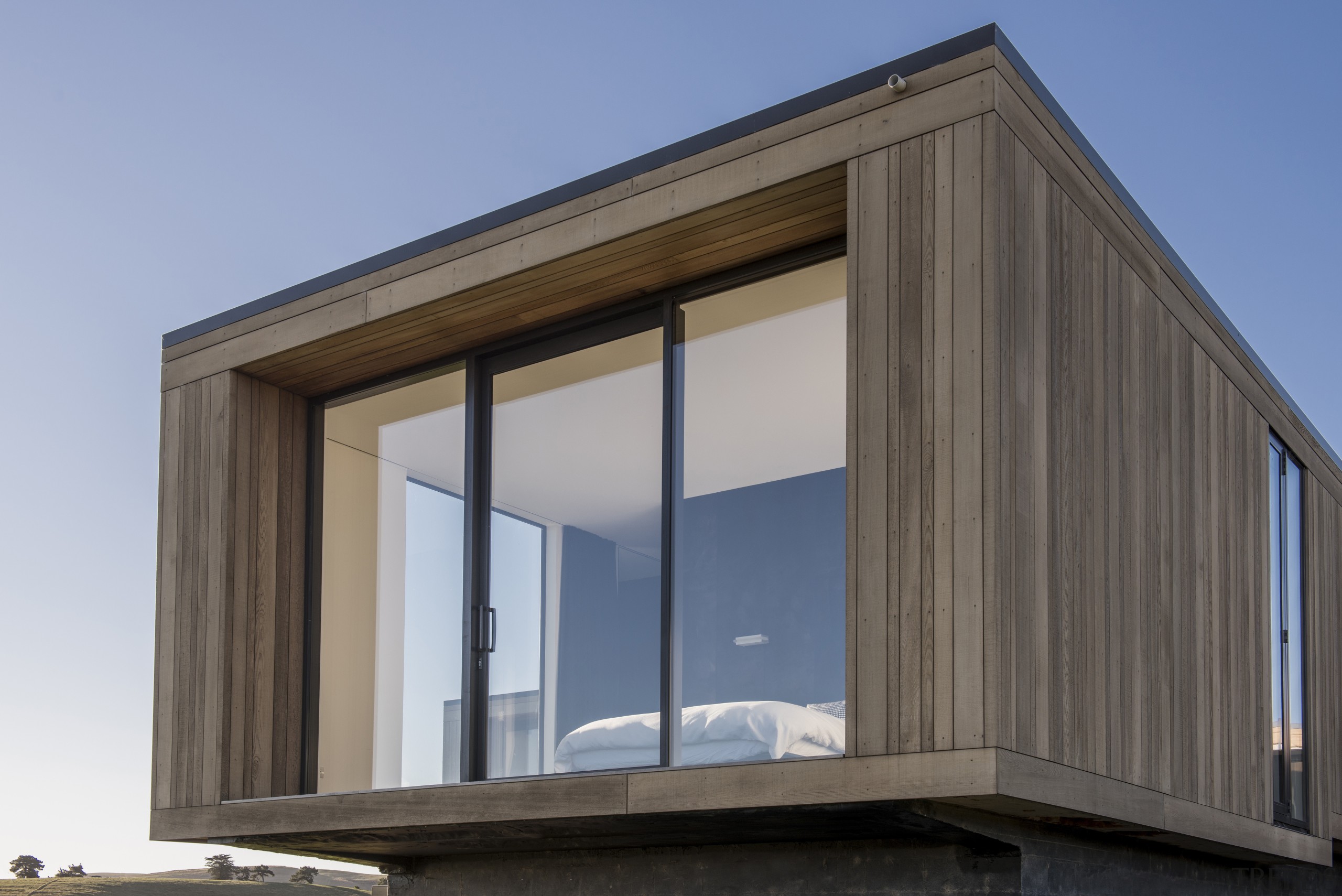 The central bedroom wing extends beyond the flanking architecture, building, facade, home, house, siding, window, gray