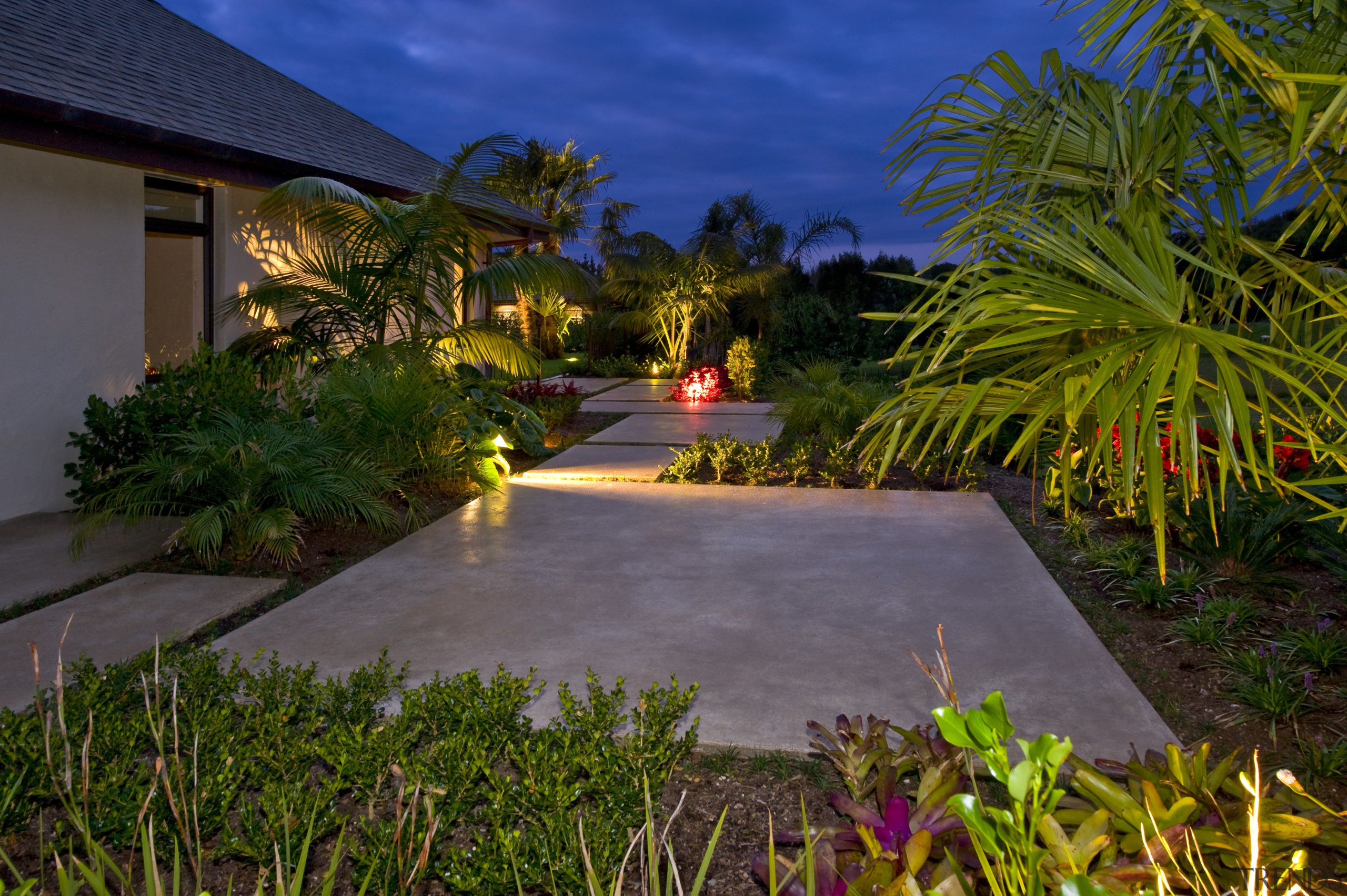 Custom flagstones from Peter Fell create the garden arecales, backyard, estate, grass, home, landscape, landscape lighting, landscaping, lighting, palm tree, plant, property, real estate, resort, sky, tropics, walkway, water, yard, brown