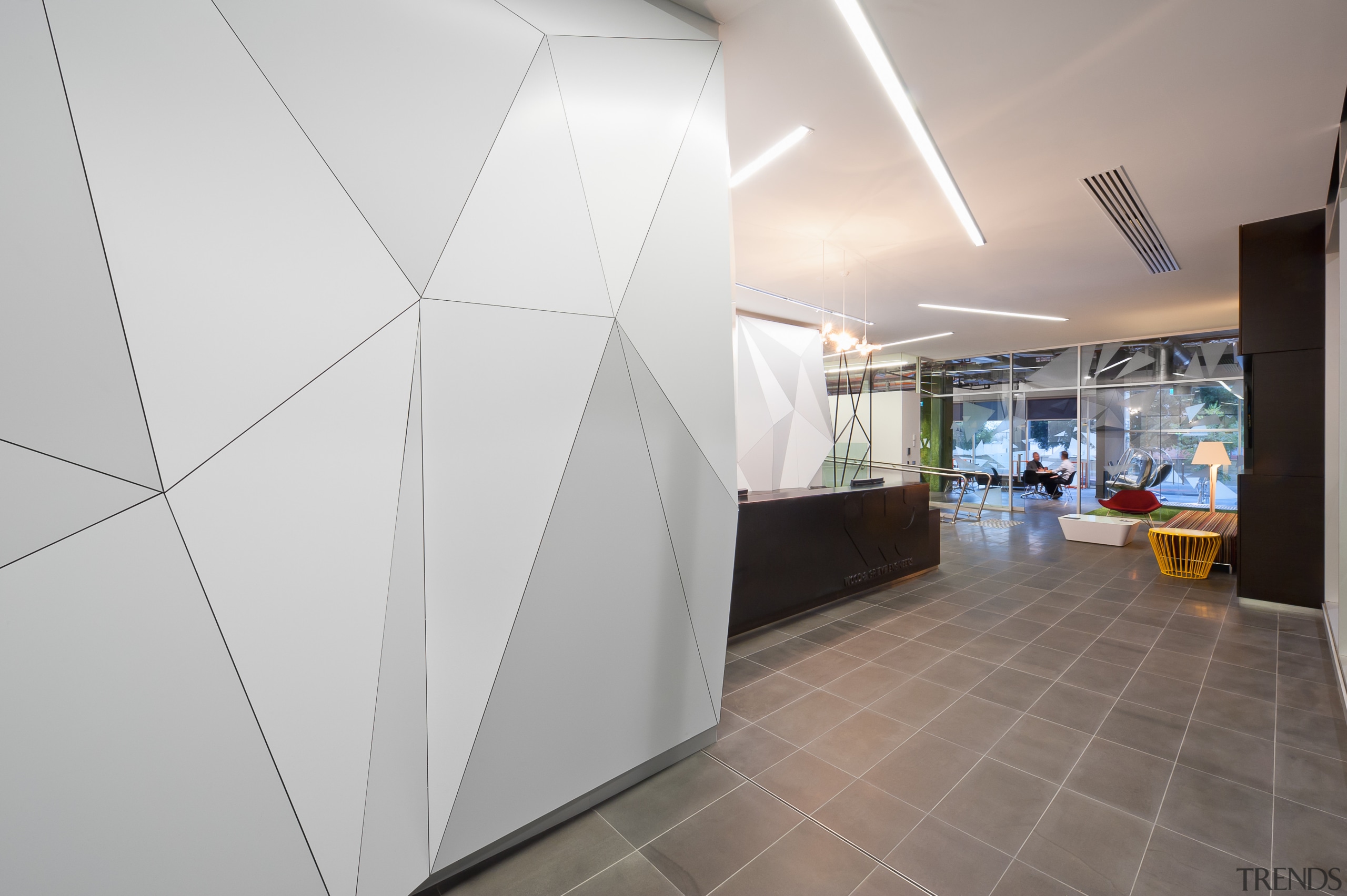 A multifaceted facade behind the reception desk of architecture, ceiling, daylighting, floor, interior design, product design, gray