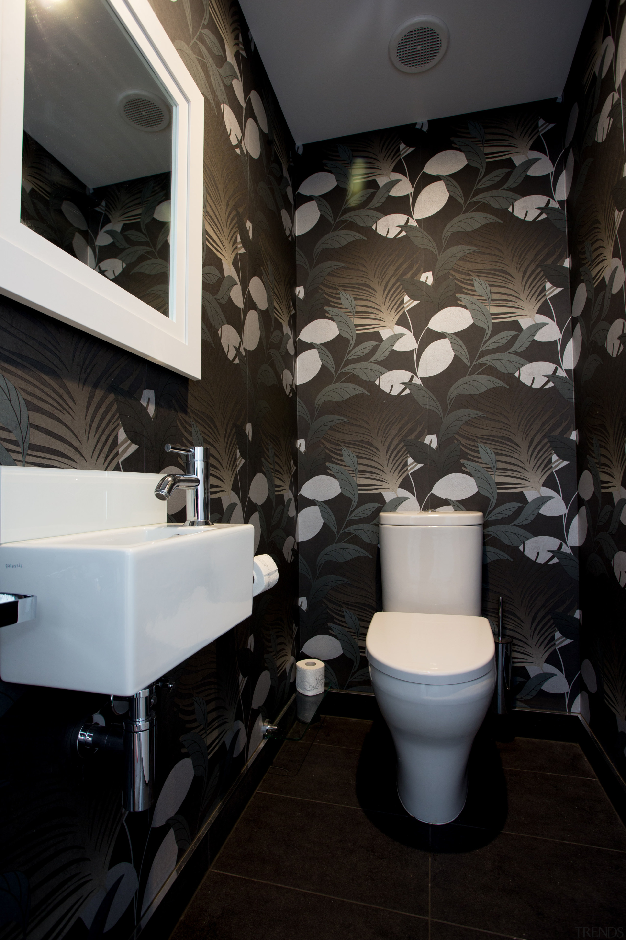 This powder room has a botanical theme, with architecture, bathroom, ceiling, floor, interior design, plumbing fixture, public toilet, room, toilet, wall, black