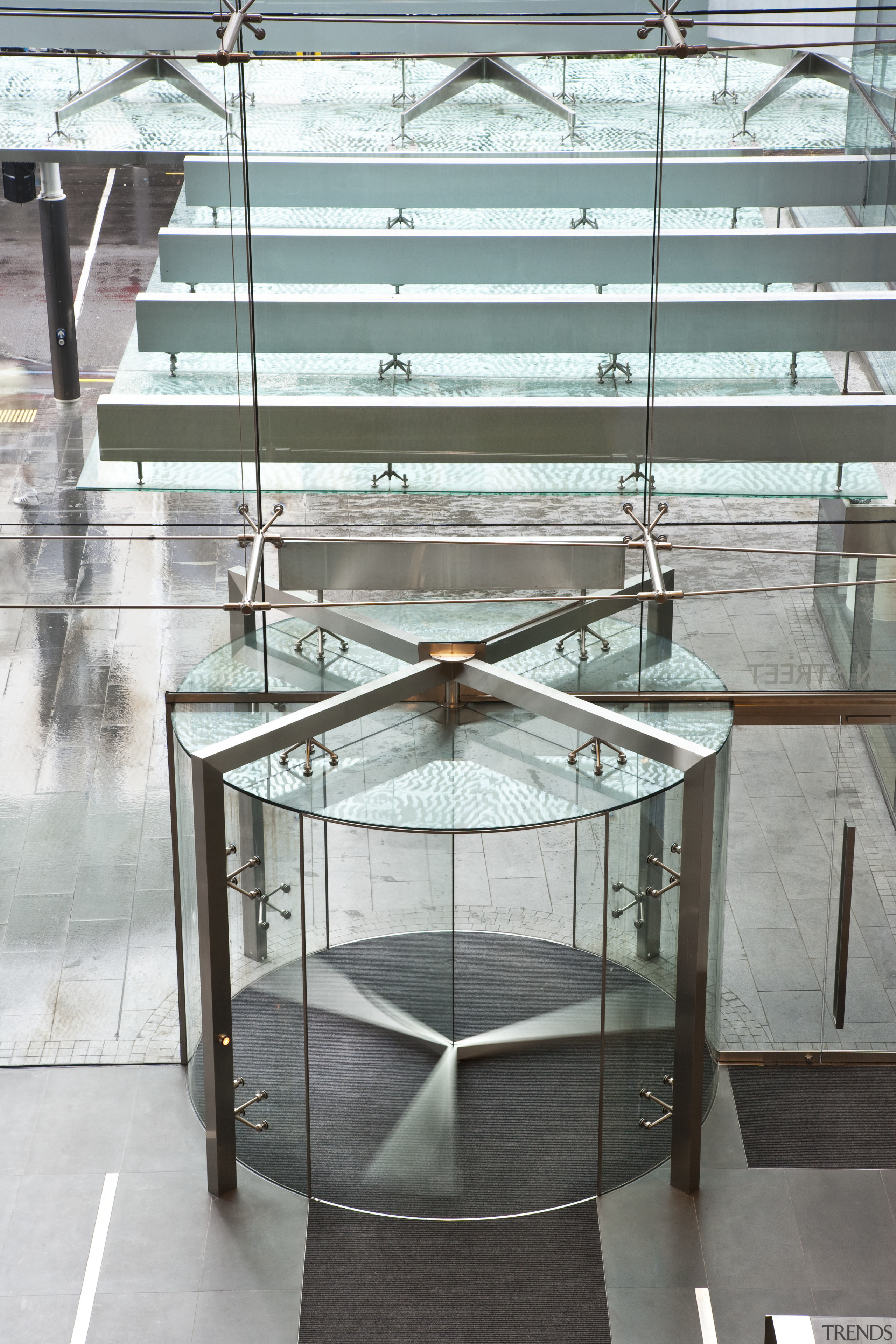 View of a frameless glass revolving door at coffee table, floor, furniture, glass, product design, table, gray, white