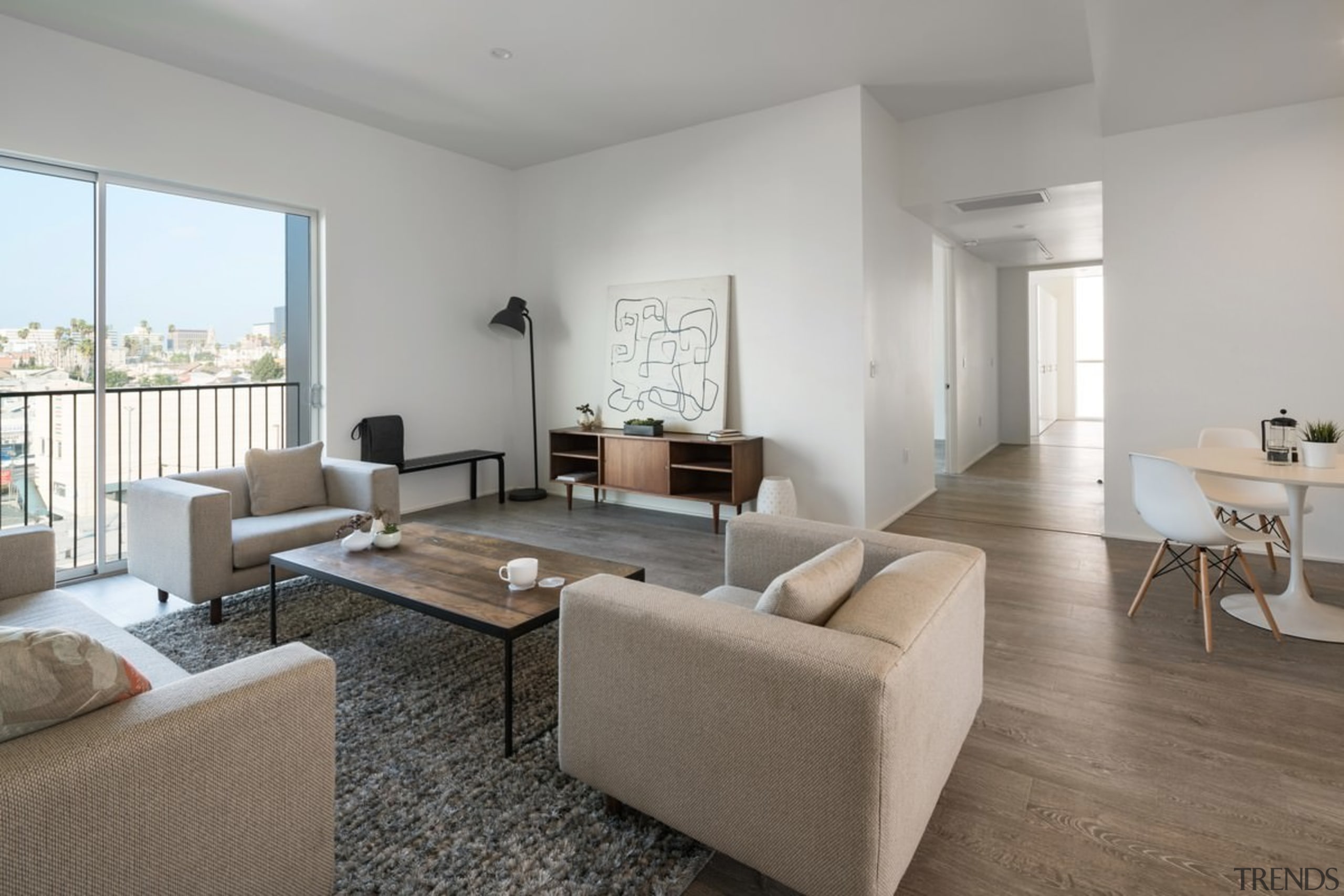 Wood-look floors line this apartment, playing off the apartment, architecture, floor, flooring, home, interior design, living room, property, real estate, room, table, gray