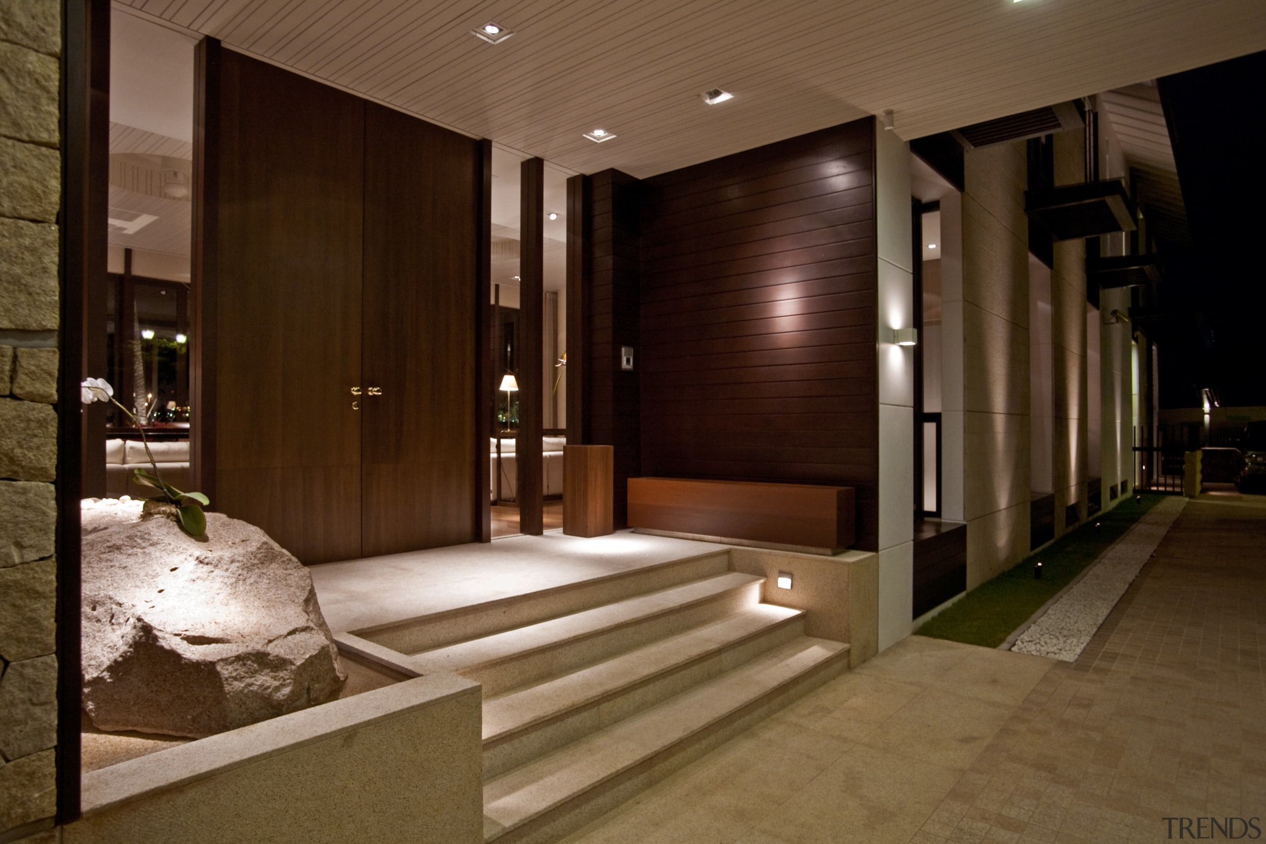 Exterior view of entrance way with paving, dark interior design, lighting, lobby, wood, brown, red