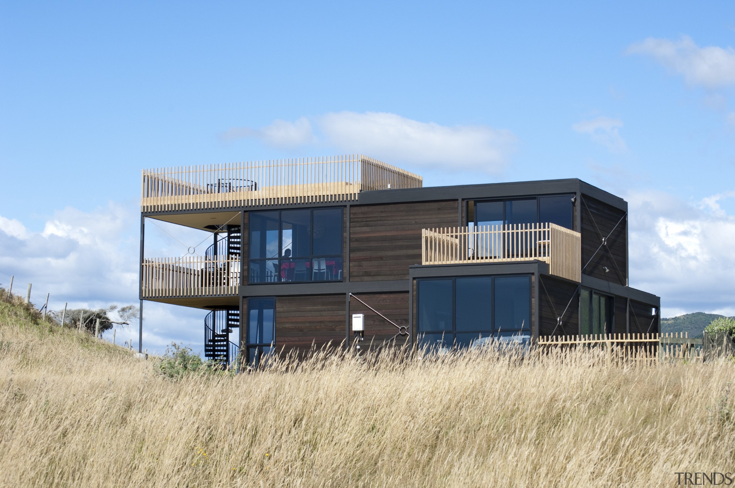 View of multi-level home with tussock landscape. - architecture, cottage, home, house, property, real estate, shack, sky, teal, orange