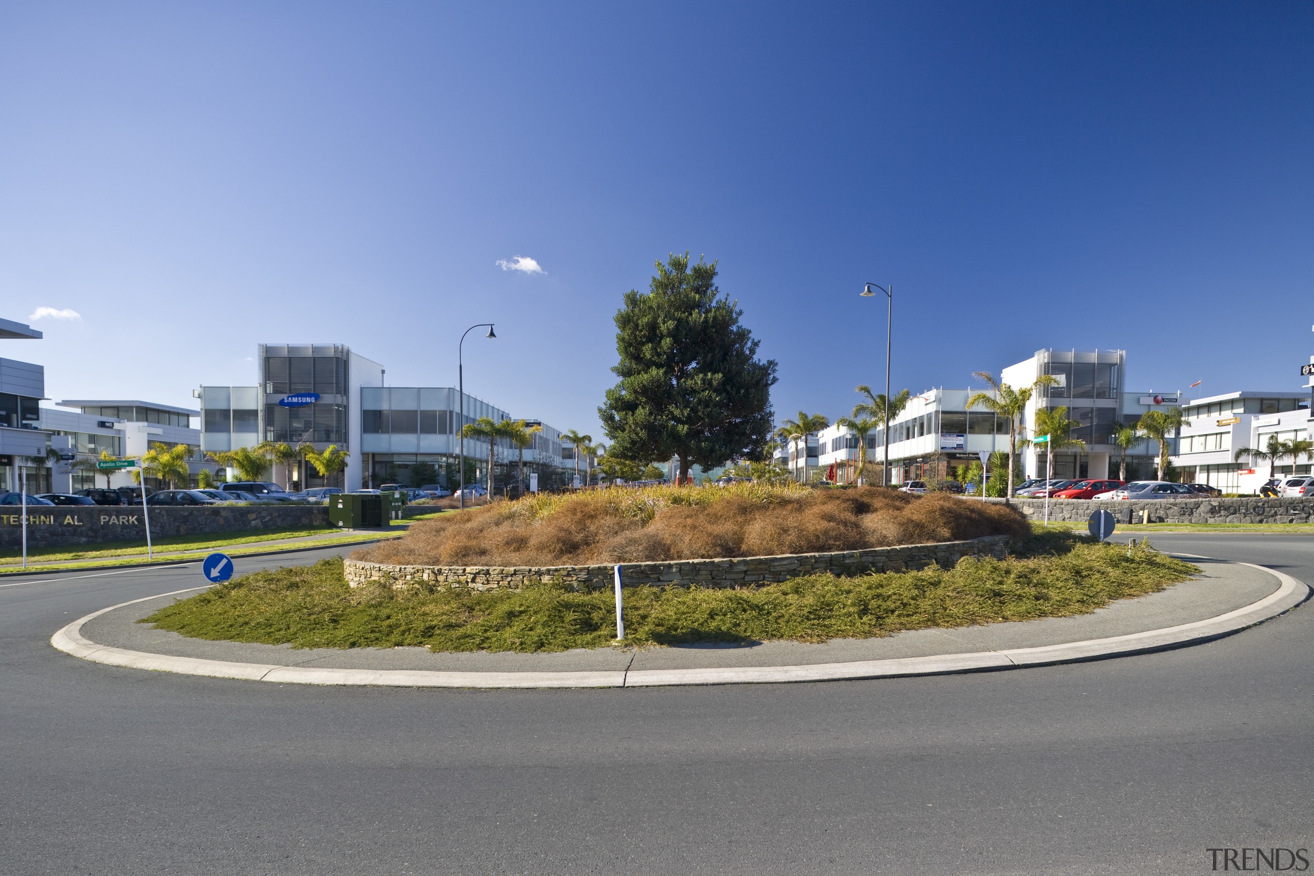 external view of inteplex@albany developed by northbridge properties. asphalt, car, city, daytime, infrastructure, neighbourhood, real estate, residential area, road, sky, traffic circle, tree, gray, teal