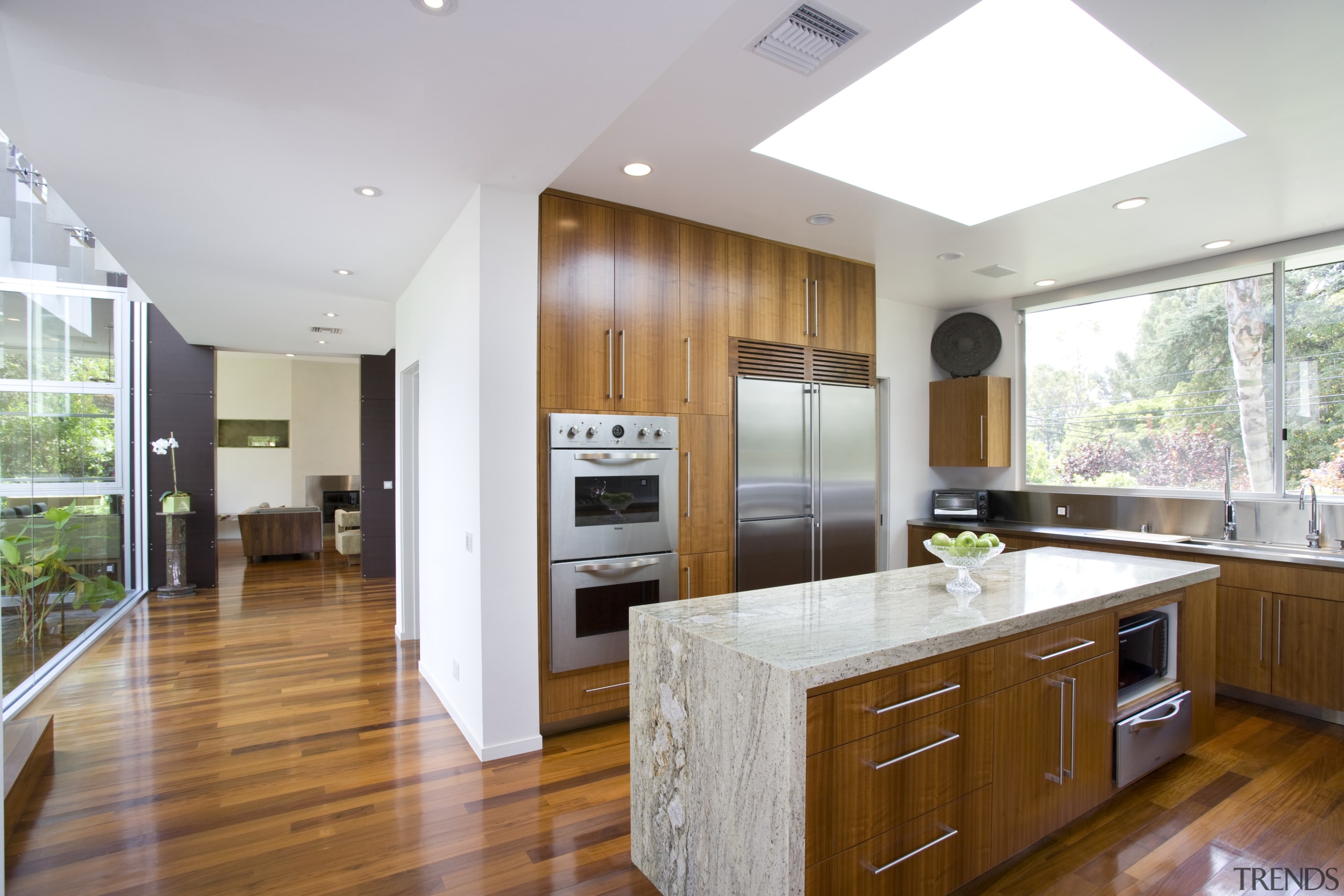 View of the kitchen featuring kitchen appliances, stainless cabinetry, countertop, floor, flooring, hardwood, interior design, kitchen, laminate flooring, real estate, room, wood flooring, white