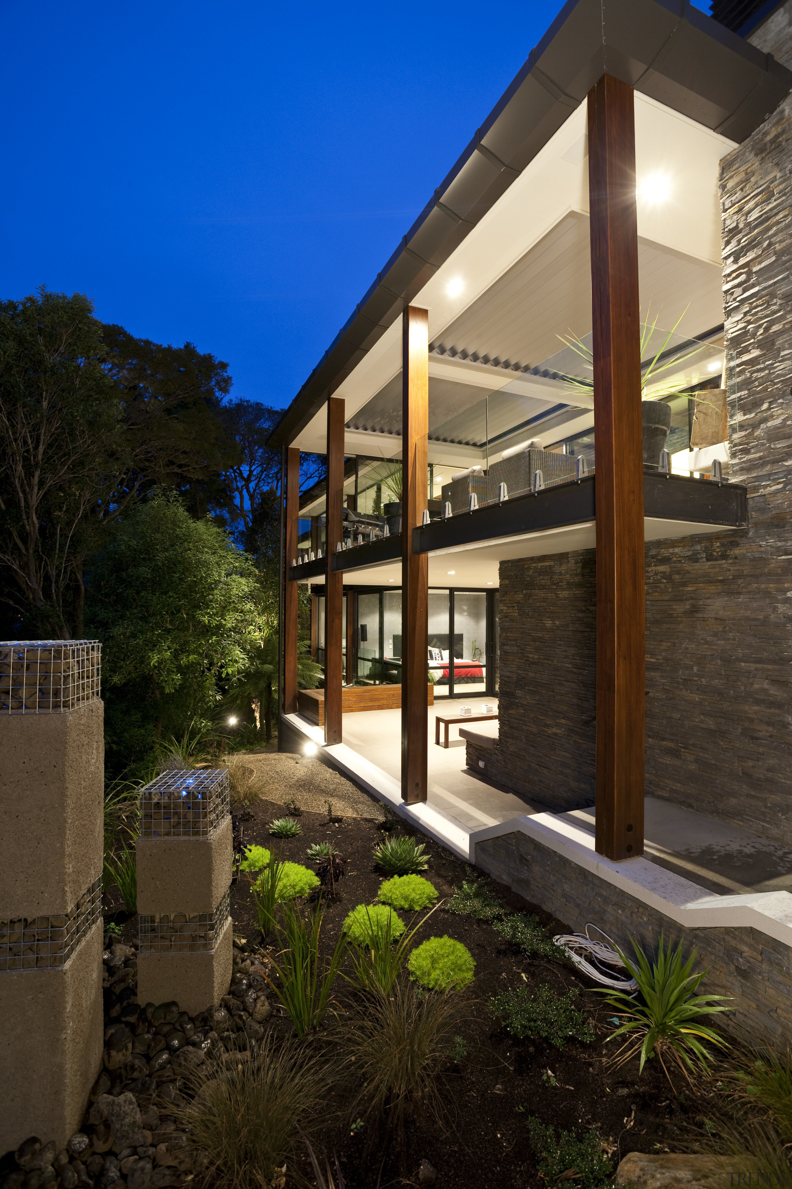 Exterior view of home which features a flat architecture, backyard, cottage, estate, facade, home, house, lighting, property, real estate, residential area, sky, window, black, brown