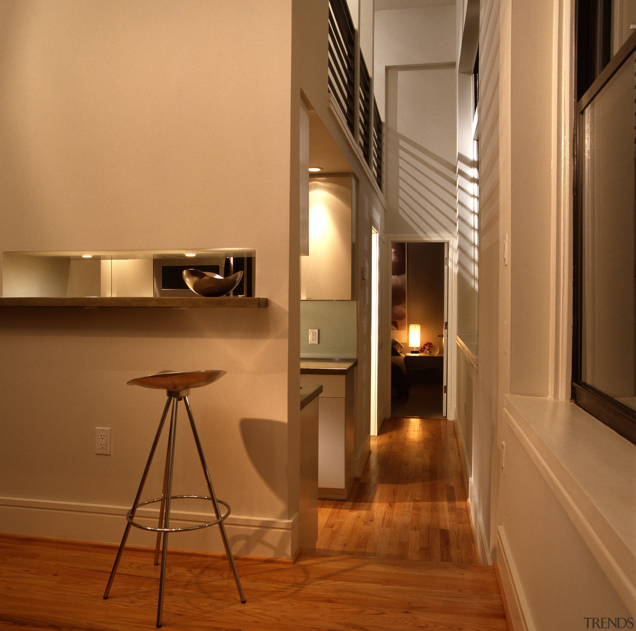 view of kitchen and living area, featuring cabinetry, floor, flooring, interior design, light fixture, lighting, loft, wood, brown, orange