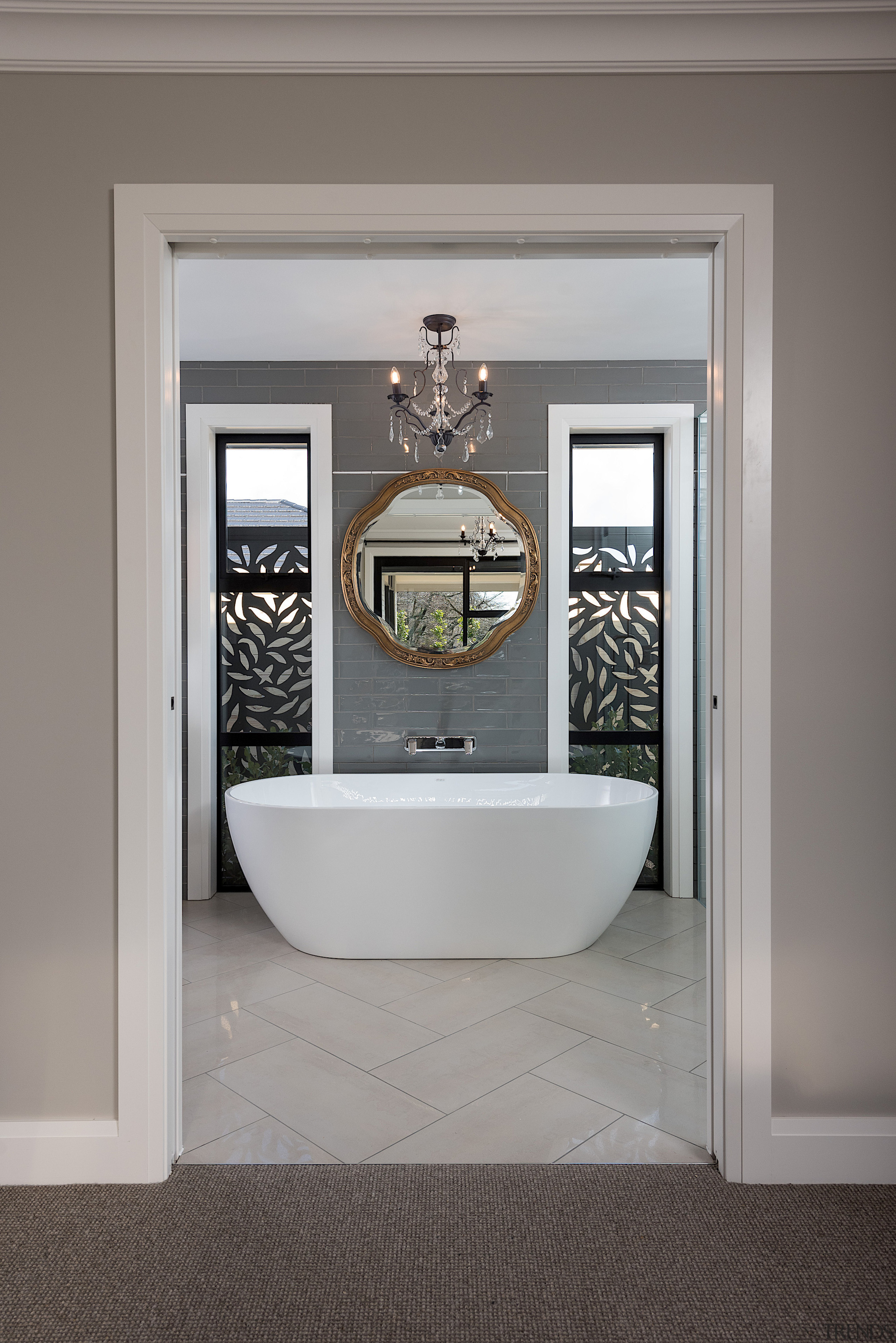 A glass chandelier hangs above the freestanding bathtub 