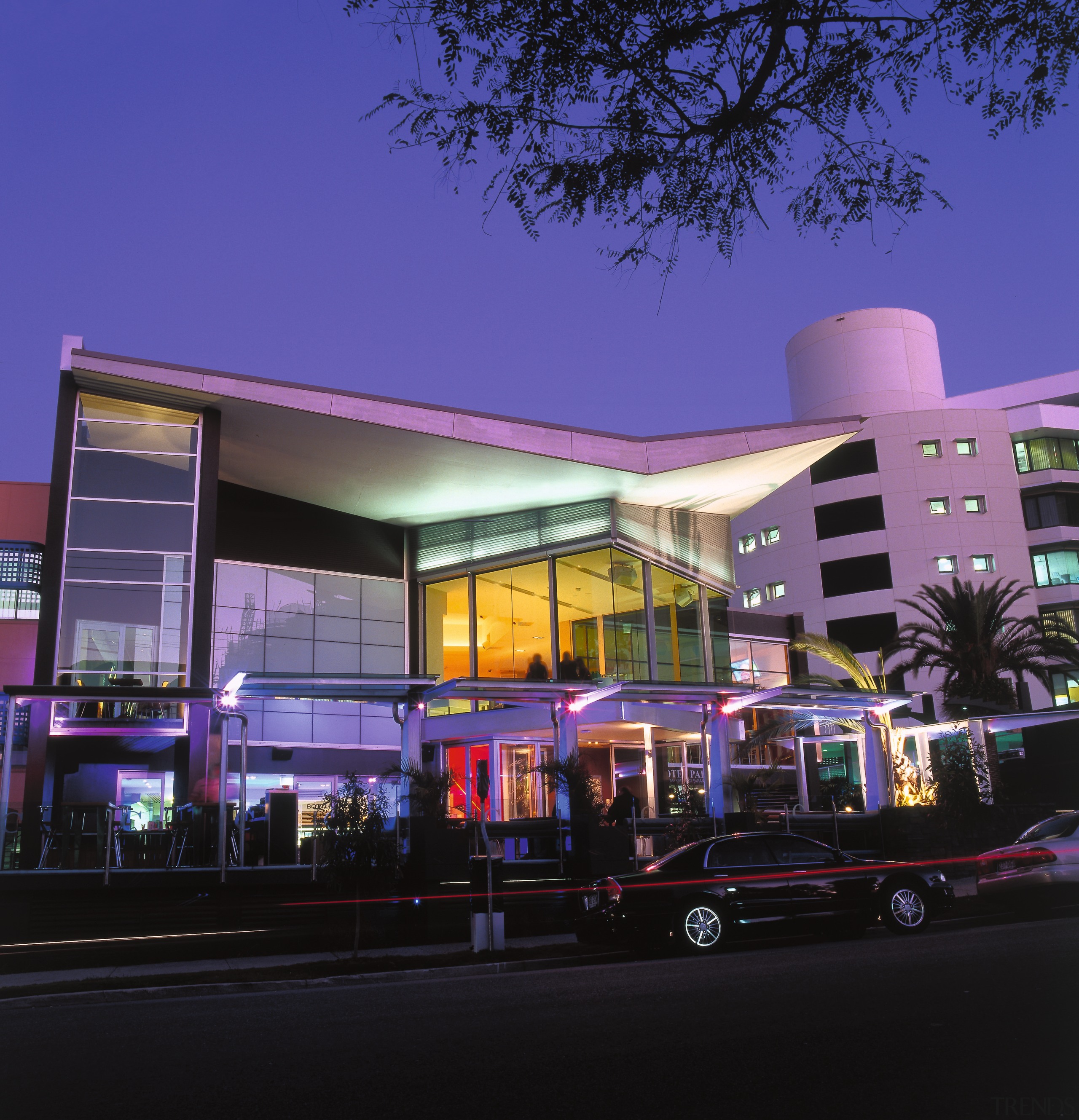 Exterior view of Coro Hotel with large windows, architecture, building, car, city, commercial building, downtown, evening, home, house, metropolis, metropolitan area, mixed use, night, residential area, sky, black, blue