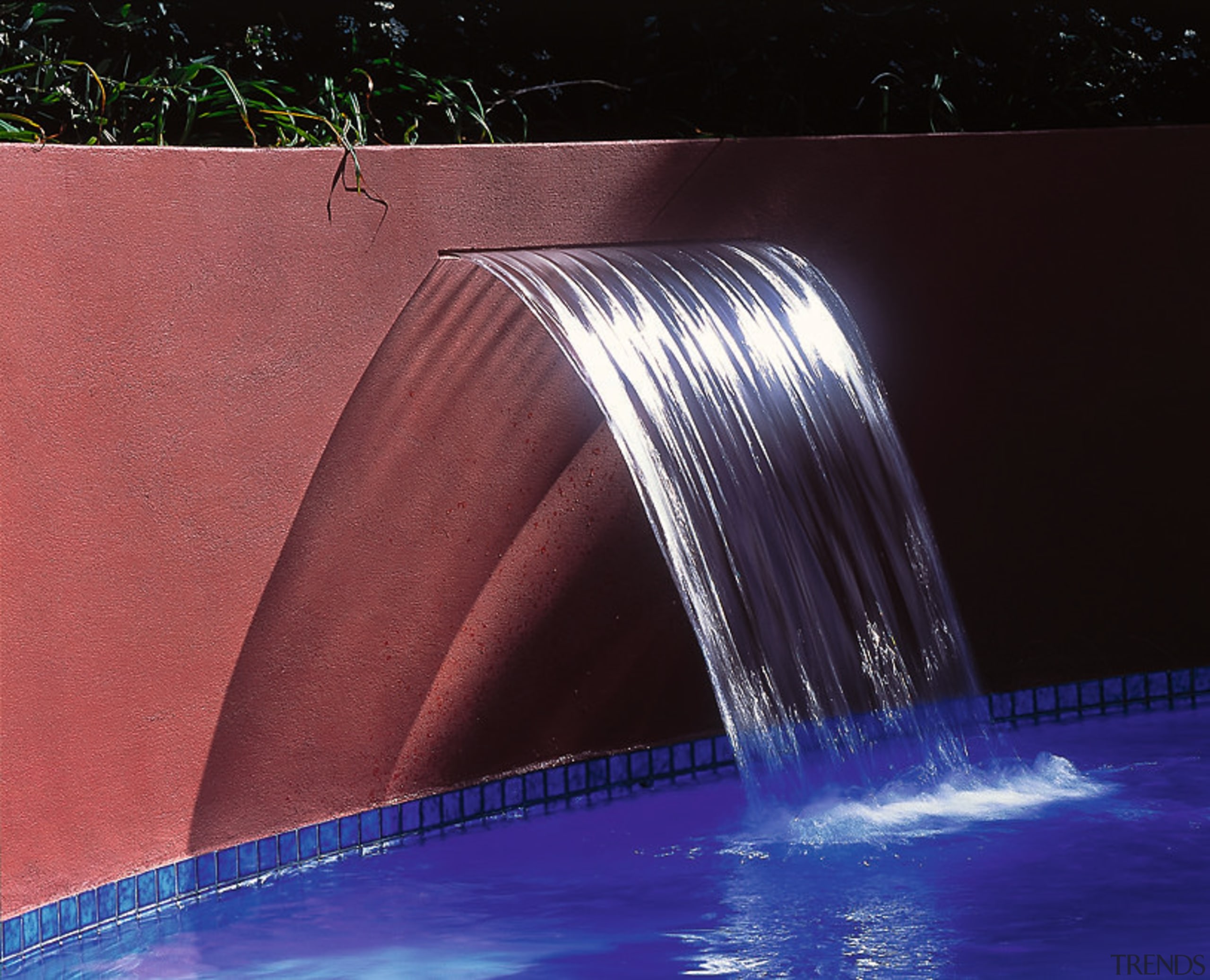 A photograph featuring a red wall with a light, lighting, reflection, water, water feature, water resources, black, red